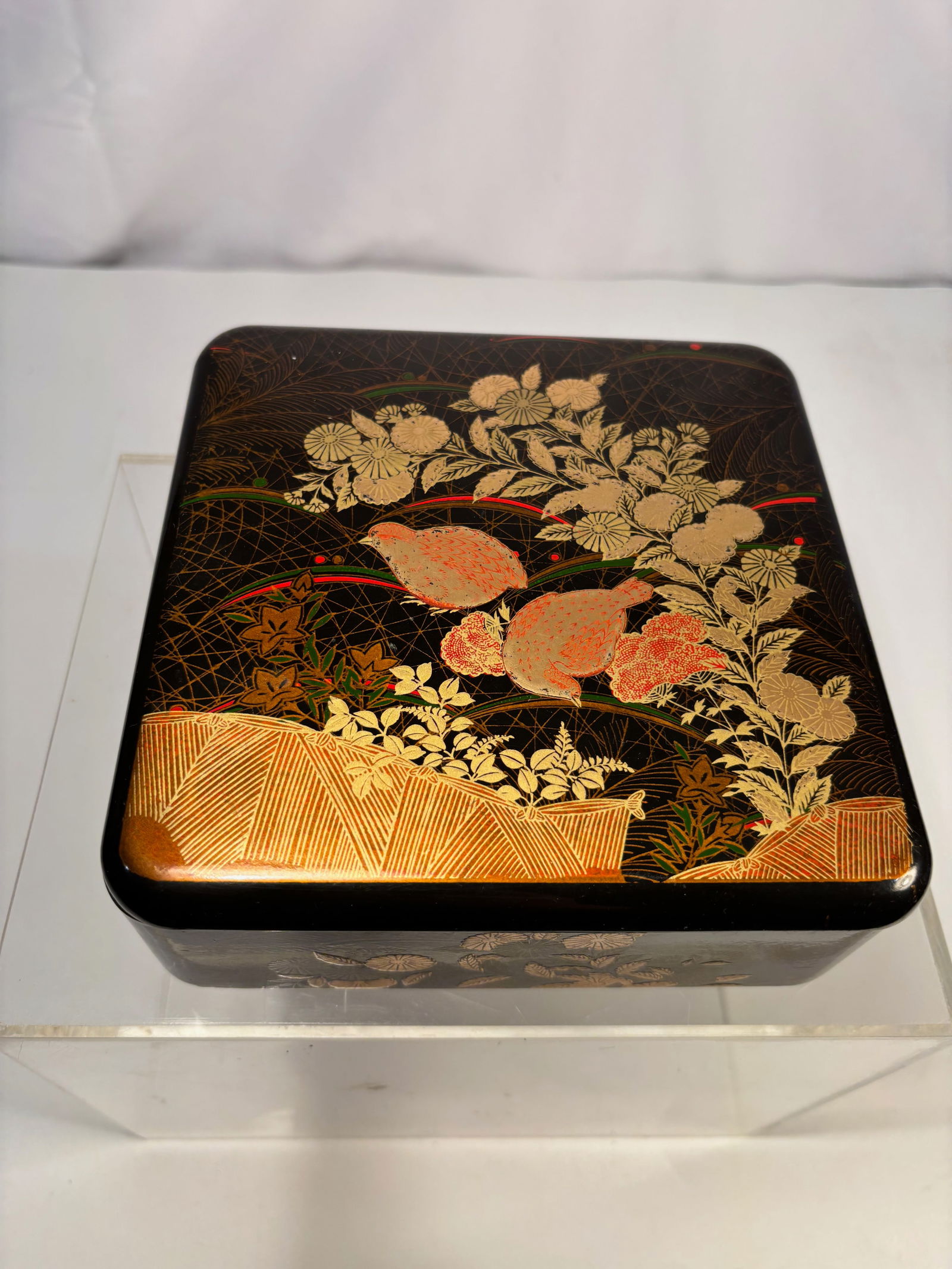 A Japanese Lacquer Box with Gilt Floral Decoration, Meiji Period (Late 19th Century): Japanese rectangular lacquer box, Meiji period (late 19th century), decorated in gilt and colored lacquer on a black ground. The lid features a dense floral composition with chrysanthemums and foliage
