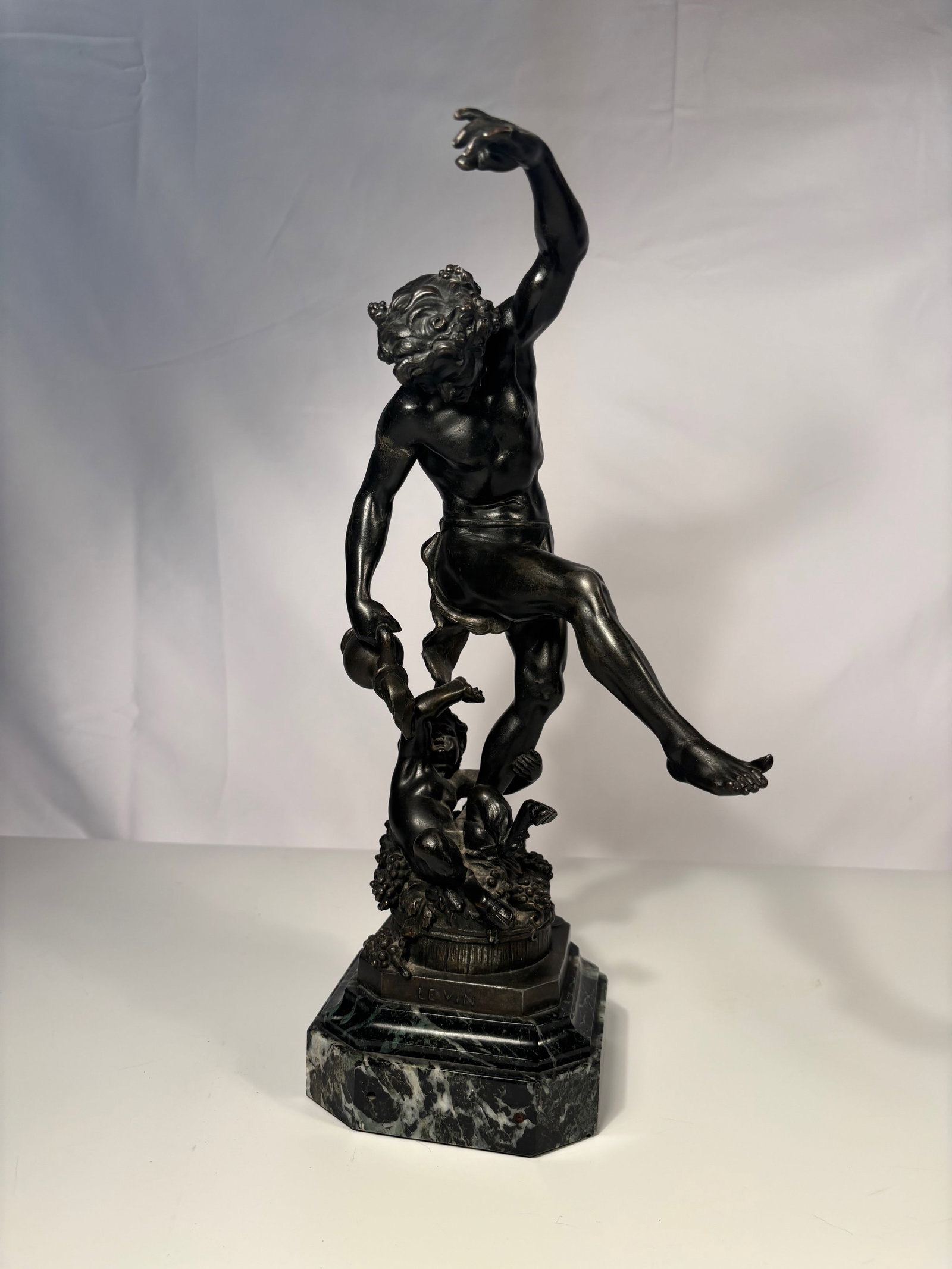 Louis Holweck (French, 1861–1935), “LEVIN?? Bronze Sculpture on Marble Base signed "Holweck": A finely cast French patinated bronze sculpture titled “LEVIN” by Louis Holweck (1861–1935), depicting a satyr-like figure dancing atop a wine barrel surrounded by grape vines and putti. The