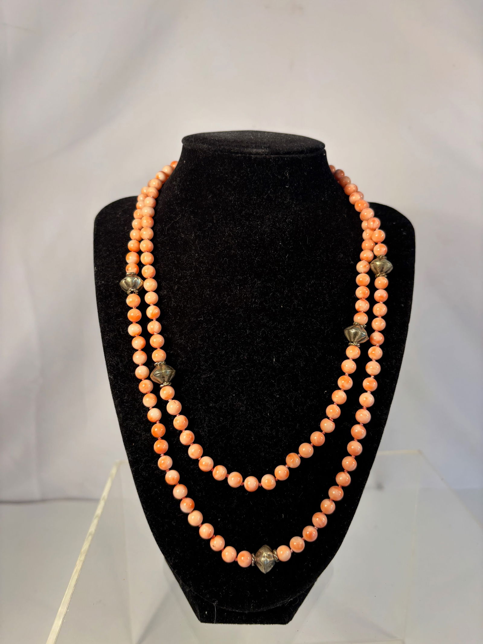 A Long natural Coral Bead Necklace with Silver-Tone Floral Spacers, 40 inches, 1.84 oz: A refined necklace composed of small round salmon-pink coral beads, accented by silver-tone floral spacer elements. The necklace is designed in an elegant long form, allowing it to be worn doubled or