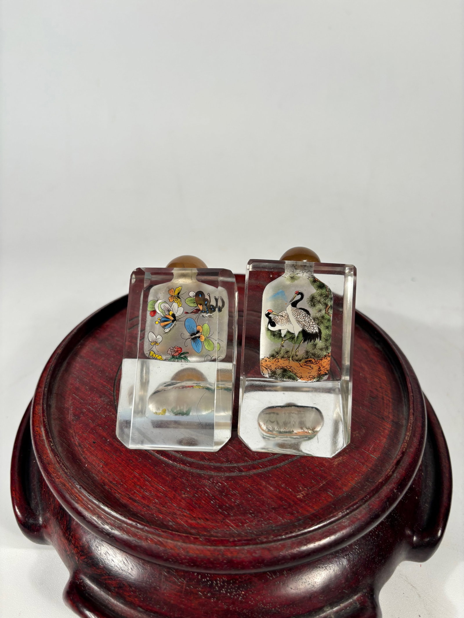 A Pair of Inside-Painted Rock Crystal Snuff Bottles: Likely Republic period, early 20th century. Each of square section and finely painted on the interior, one bottle depicting a pair of cranes standing beneath pine trees, symbolizing longevity and good