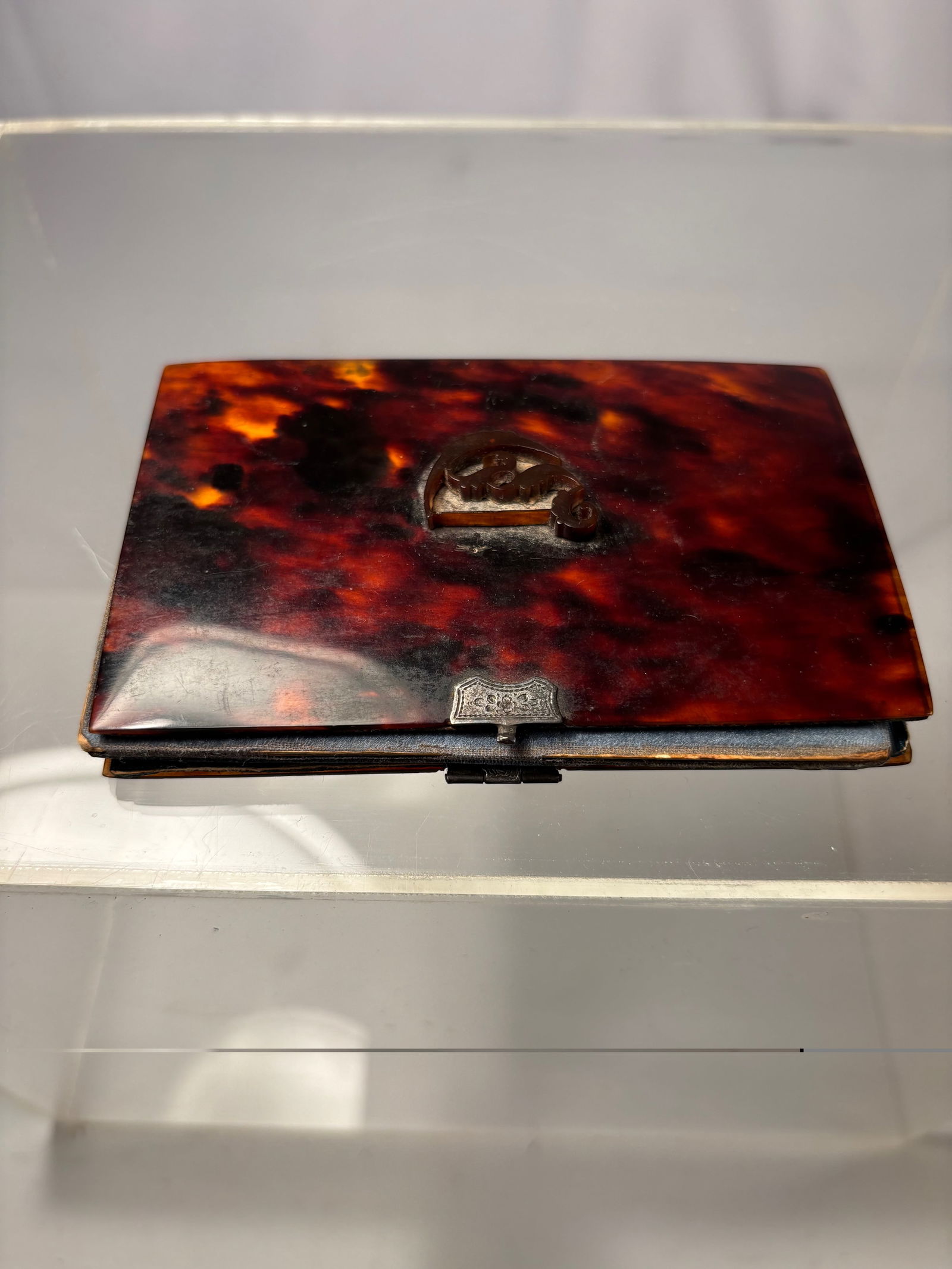 A shell Case with Persian Miniature Painting, 19th Century: A fine Persian booklet, the exterior fashioned from richly mottled shell in deep amber and crimson tones, fitted with a metal clasp. The interior opens to reveal a recessed compartment lined in blue s