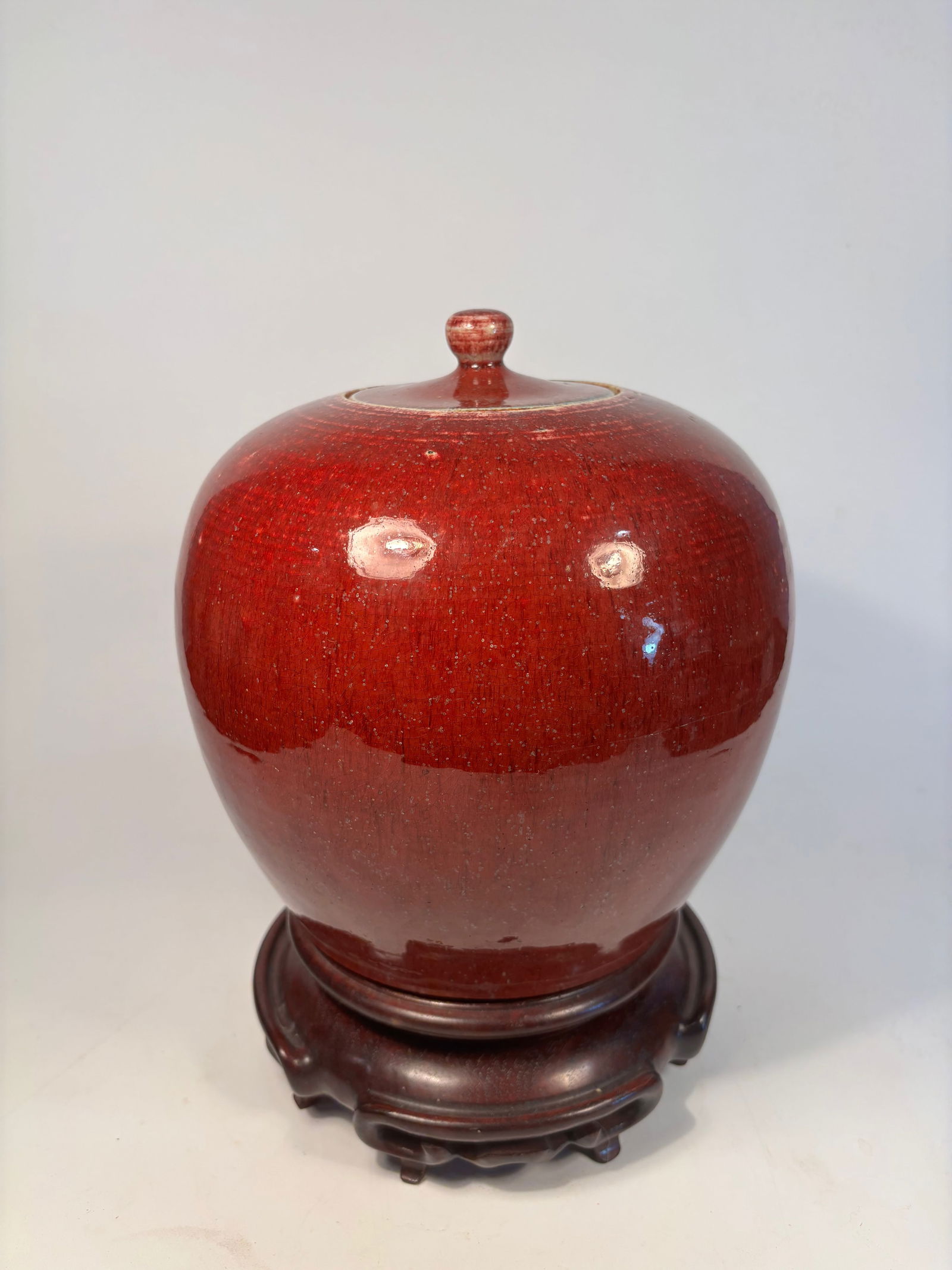 A Chinese Flambé-Glazed Porcelain Jar and Cover,: 19th Century; A Chinese flambé-glazed porcelain jar with cover, likely 19th century. The globular body is covered in a rich, mottled oxblood red glaze (langyao hong) with characteristic streaking and