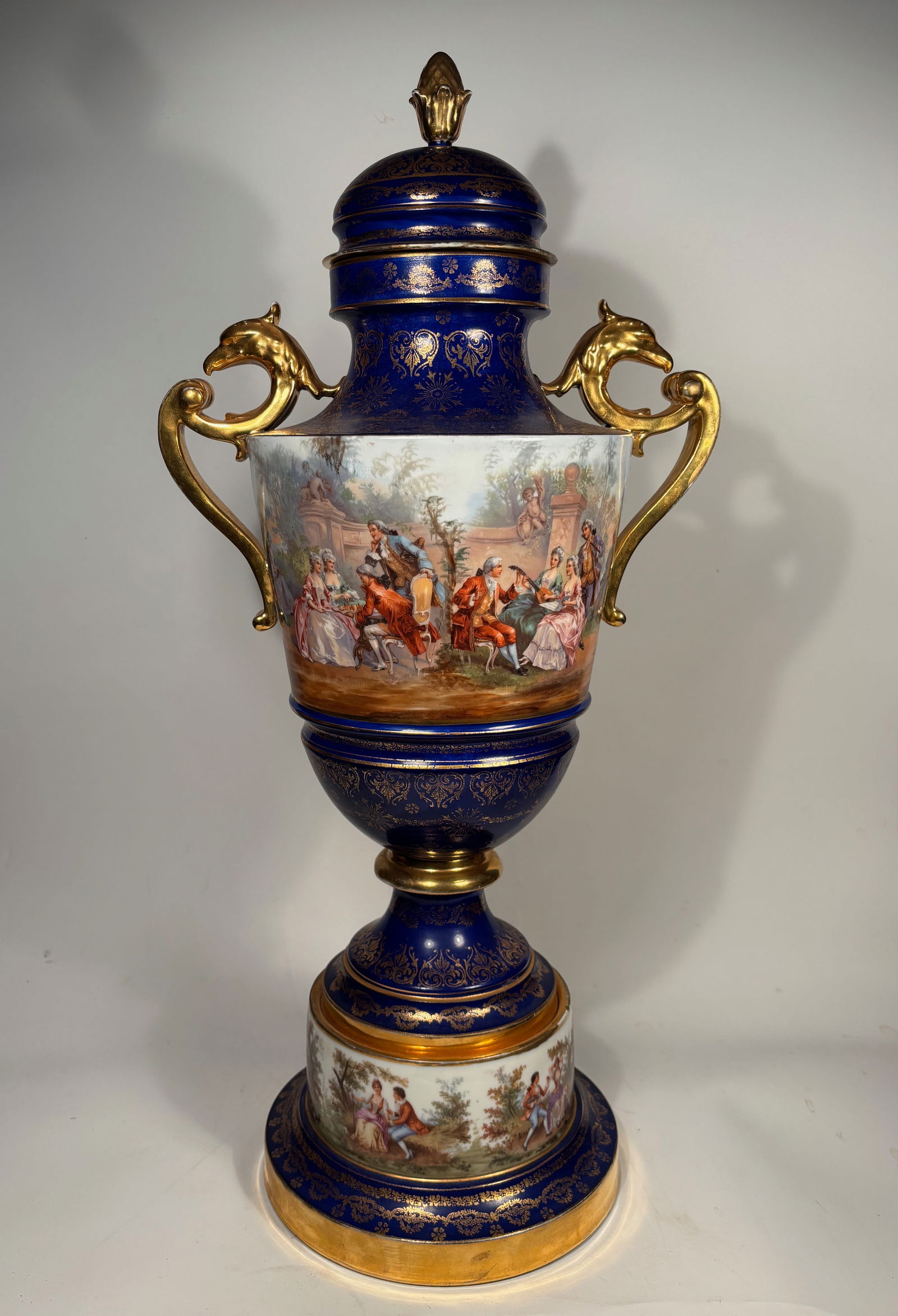 A Large Austrian Royal Vienna Porcelain Covered Bolted Urn: A large and impressive 19th-century Austrian Royal Vienna-style porcelain bolted urn with cover. The urn features a rich cobalt blue (“bleu de roi”) ground with extensive gilt decoration throu