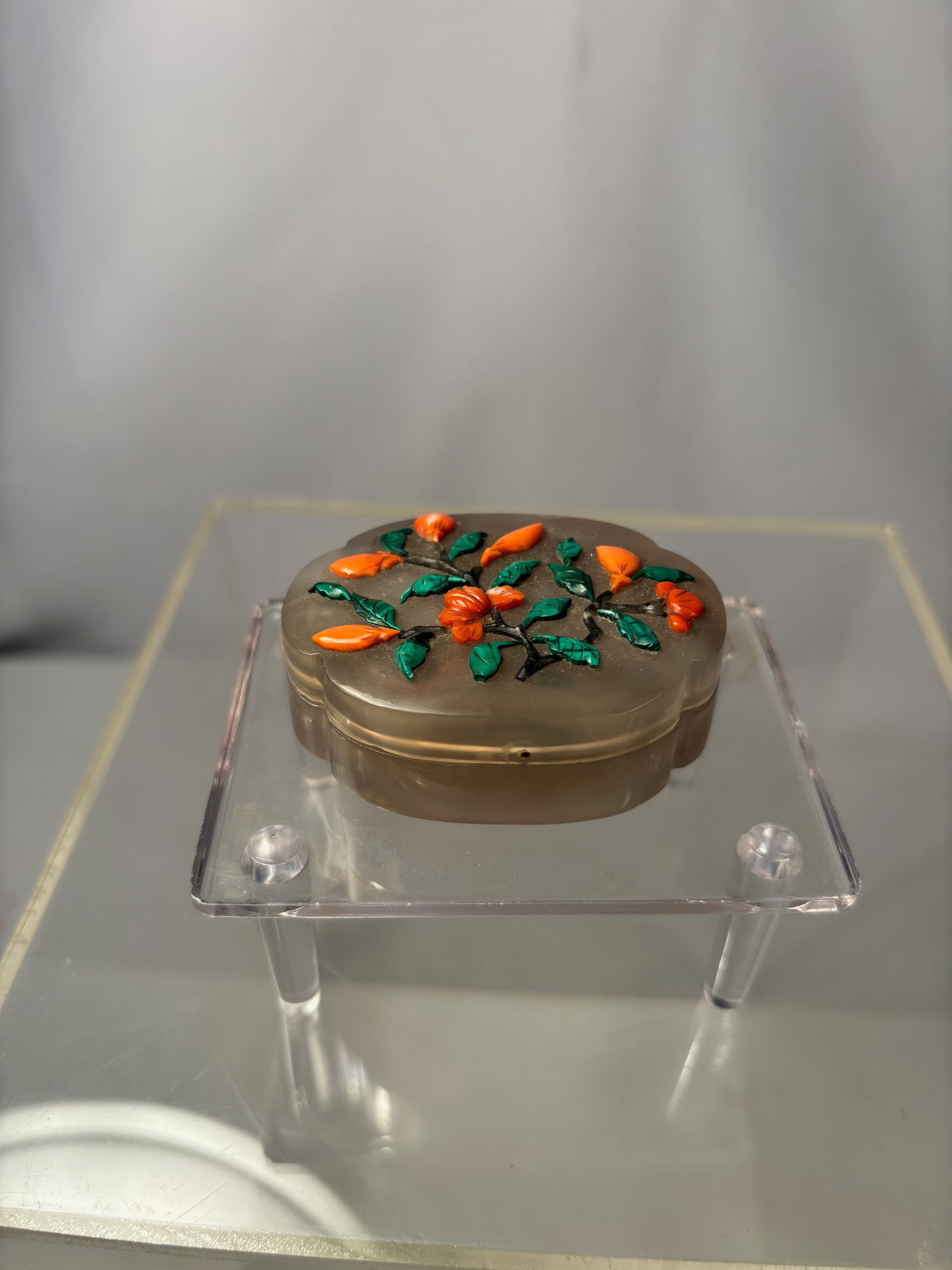 A Hand Carved Agate Box with Coral and Malachite Floral Motif: An agate box with lid, formed from a translucent material, featuring raised applied floral decoration in coral and malachite tones. The floral elements are applied to the surface rather than carved
