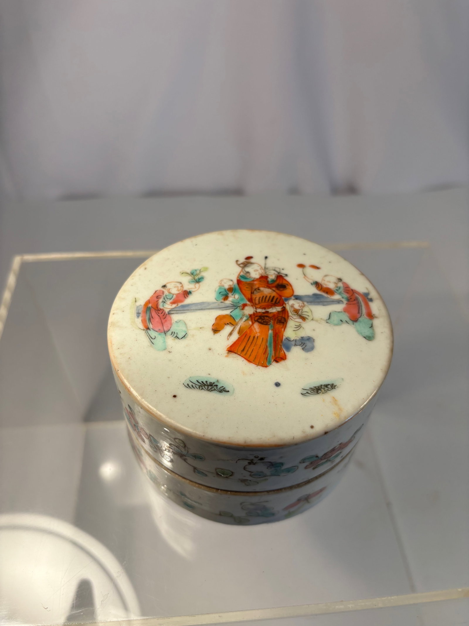 A Chinese Famille Rose Enamel Circular Covered Box with Figures: Qing Dynasty, 19th Century; Finely hand-painted in soft famille-rose enamels with a continuous band of floral sprays around the sides, the cover depicting two court ladies in brightly colored robes wi