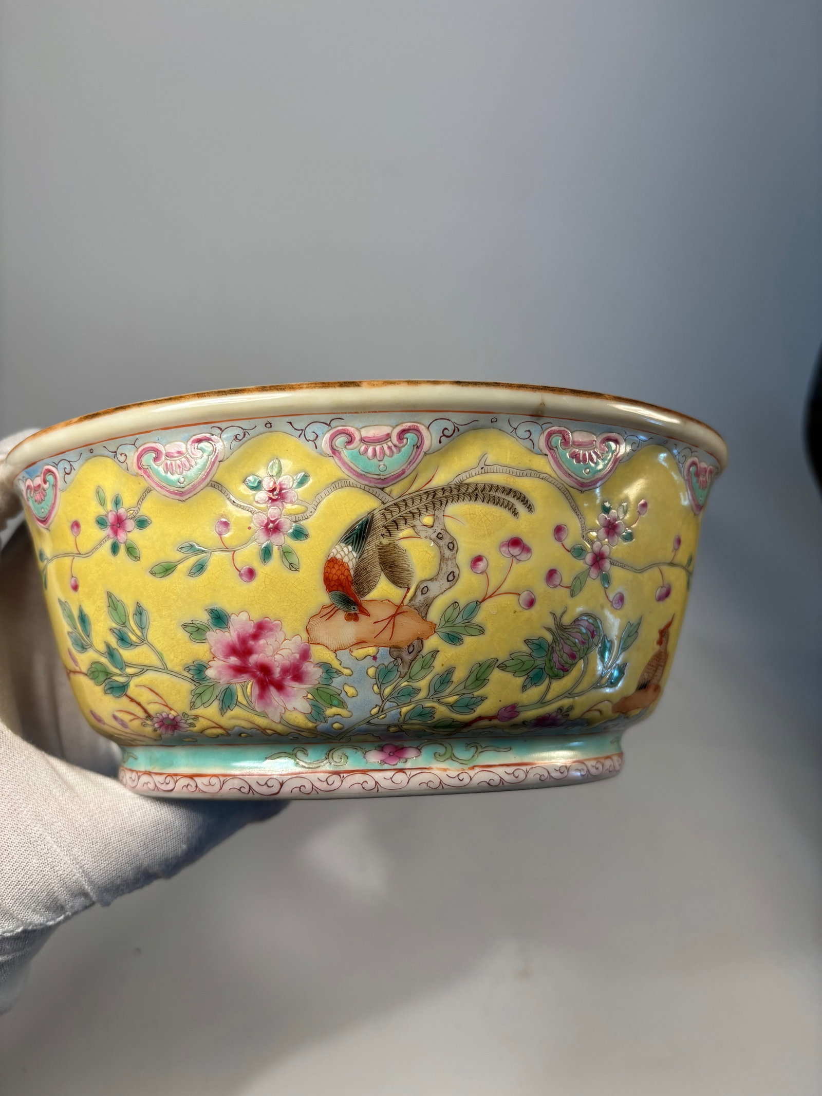 A Chinese Famille Rose Yellow-Ground Jardinière with Birds and Peonies: 19th century: Featuring a central scene of pheasants perched among blossoming peony branches. The rim is bordered with a ruyi scroll design and the interior is finished in turquoise glaze. The base be