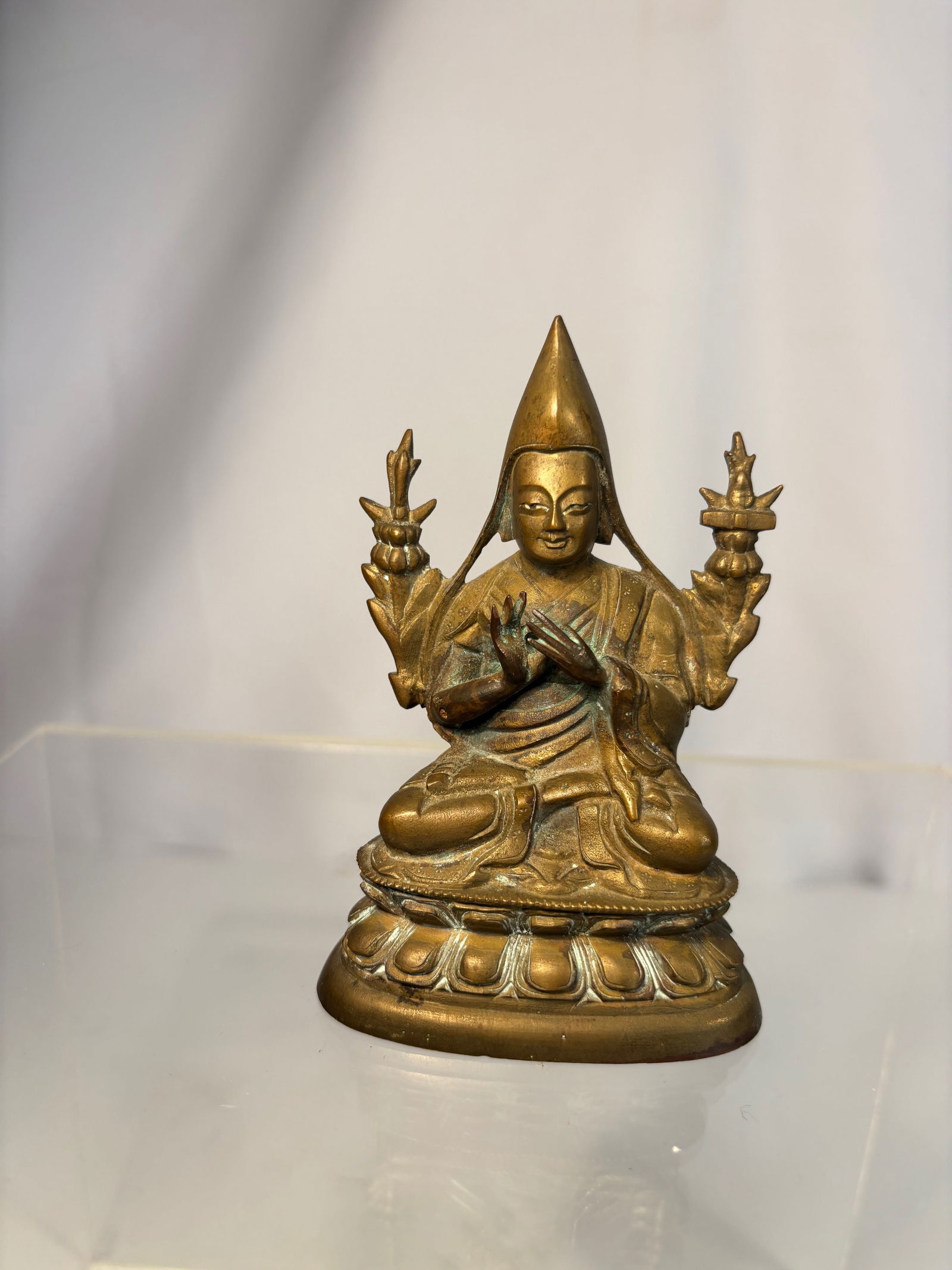 Gilt-Bronze Figure of Tsongkhapa, Tibet, 18th–19th Century: A finely cast gilt-bronze figure of Tsongkhapa, the revered founder of the Gelug (Yellow Hat) sect, shown seated in vajrasana on a double-lotus base. His hands are held in the dharmachakra mudra (gest