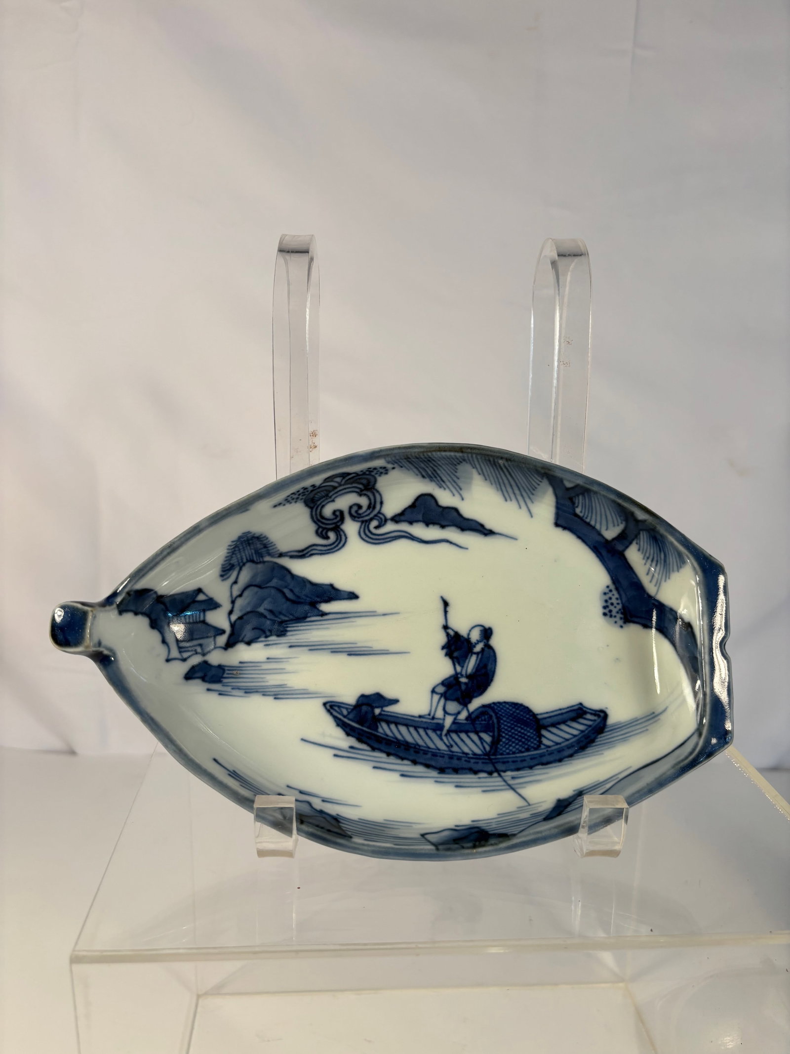 A Japanese Blue and White Boat-Shaped Porcelain Dish: Meiji period(1868-1912);Boat-shaped Japanese porcelain dish, decorated in underglaze cobalt blue with a central chrysanthemum motif and scrolling foliage panels to the sides, the form with gently