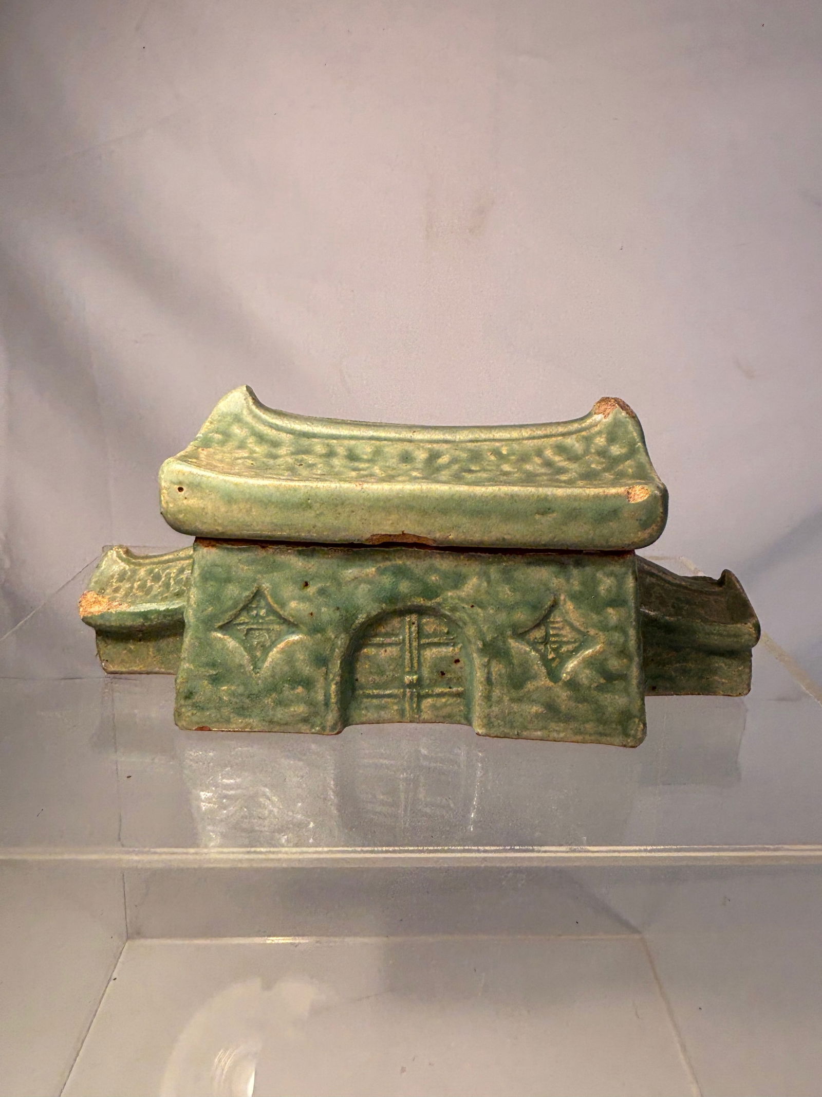 An Asian/Japanese Green-Glazed Pottery Inkwell in the Form of a House, with Cover: 19th-20th century; An Asian green-glazed pottery inkwell, formed as a miniature house with removable cover, in the style of Han dynasty tomb models. The rectangular body with molded geometric decorati