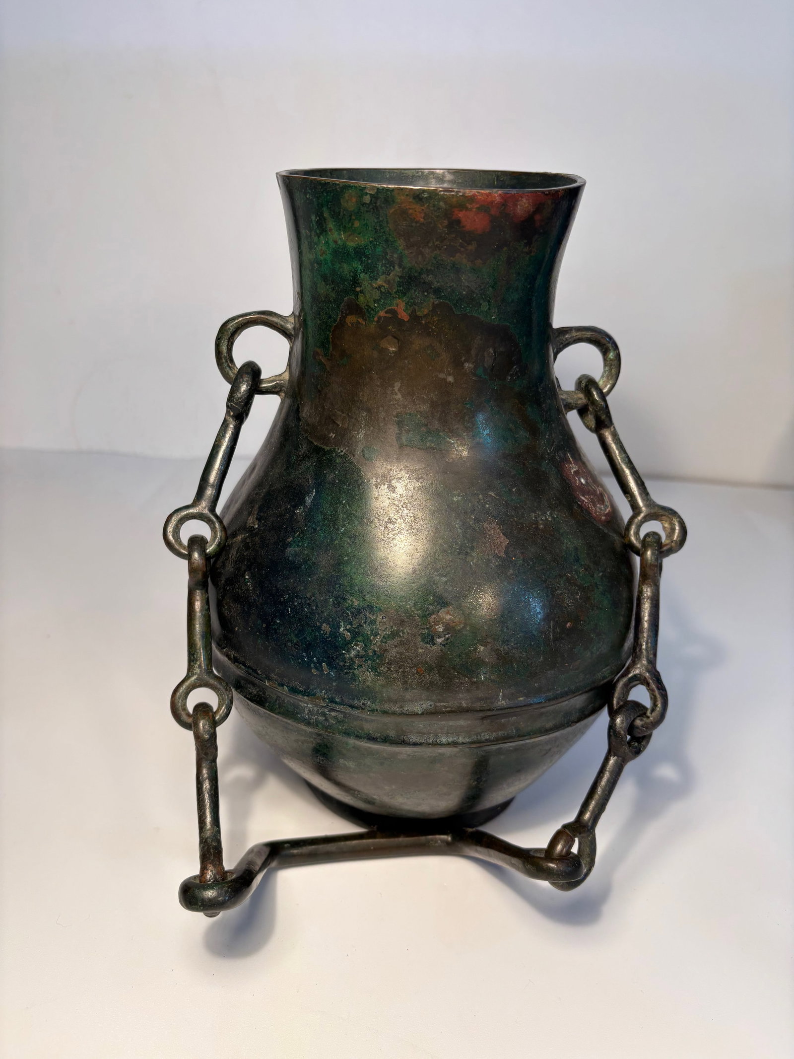 A Chinese Bronze Ritual Wine Vessel , HU: EARLY ZHOU DYNASTY , SRPING AND AUTUMN PERIOD, 6TH CENTURY ; The pear-shaped body with a double bow-string band cast mid-body which is interrupted by a ring handle, each of the ring handles on the nec