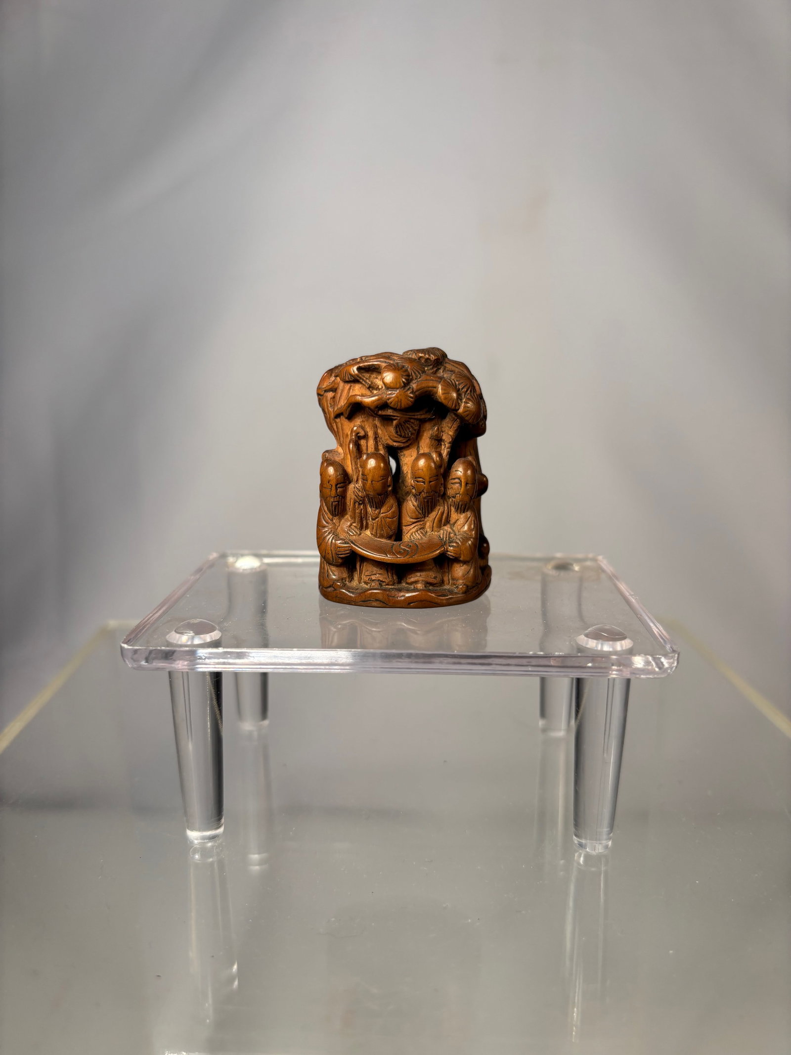 A Chinese Carved Boxwood Seal with Immortal Figures and Shou Medallion Base: Qing Dynasty (1644-1912); A Chinese carved boxwood seal finely worked with a detailed figural scene depicting immortals and attendants arranged in a layered composition. The figures are carved in high