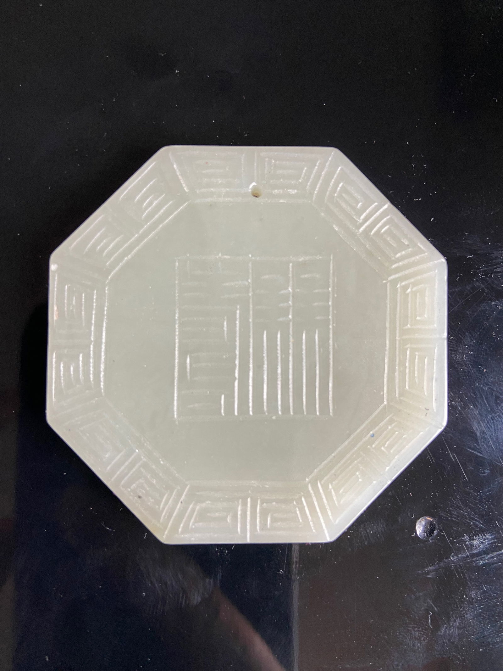 A CHINESE OCTAGONAL SHAPE WHITE NEPHRITE JADE PLAQUE: Qing Dynasty (1644-1912);The OCTAGONAL SHAPE Plaque is finely carved with Chinese characters and flower motifs;The jade is of an even pale tone.Dimensions? Height: 5.5cm ;thickness: 6mm.