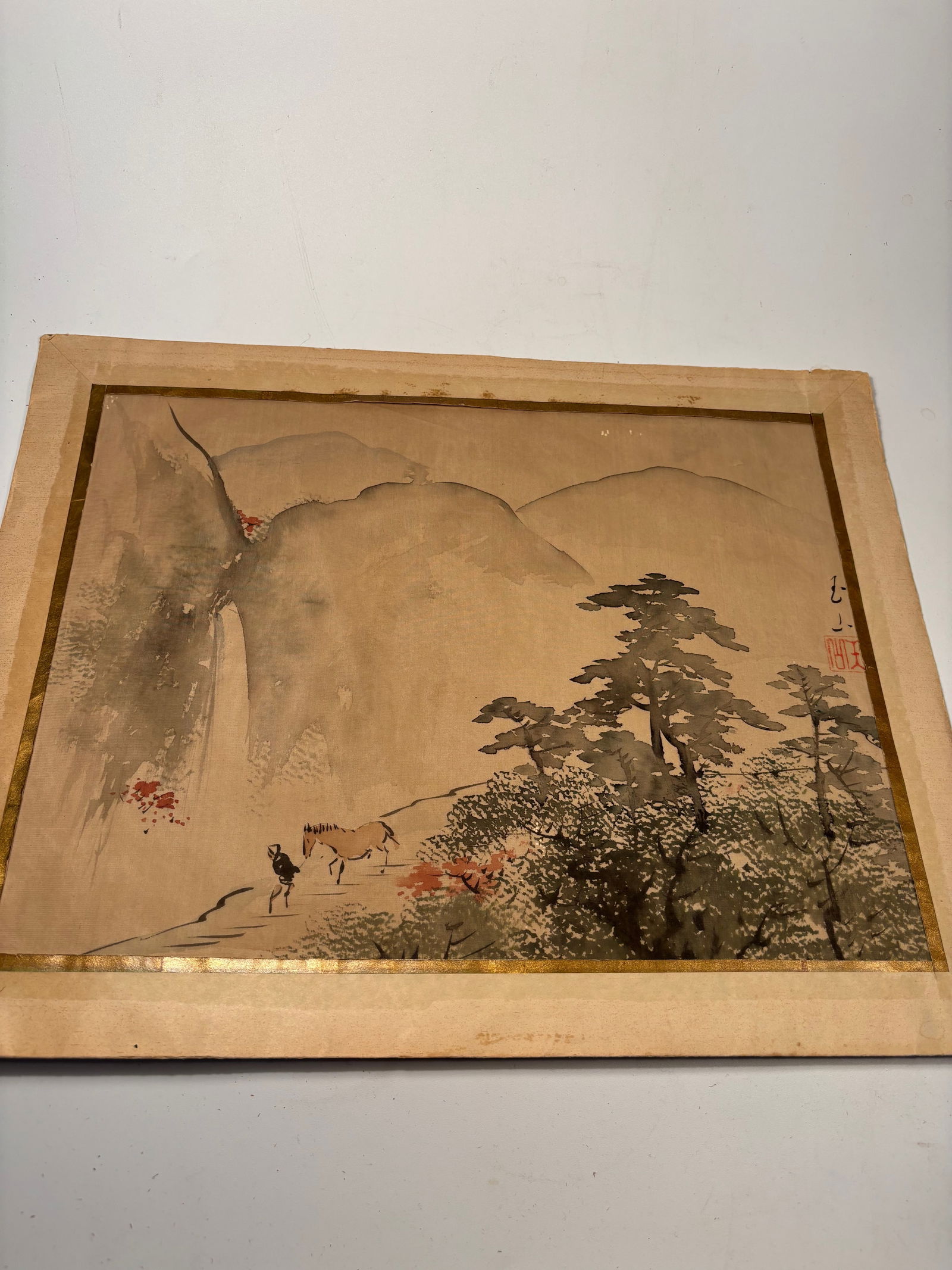A Japanese water color paint on silk Signed Gyokuzan (??): 19th century; A finely painted Japanese watercolor on silk, depicting a scholar or traveler crossing a rope bridge through misty mountain scenery with towering cliffs and pines. The scene is rendered