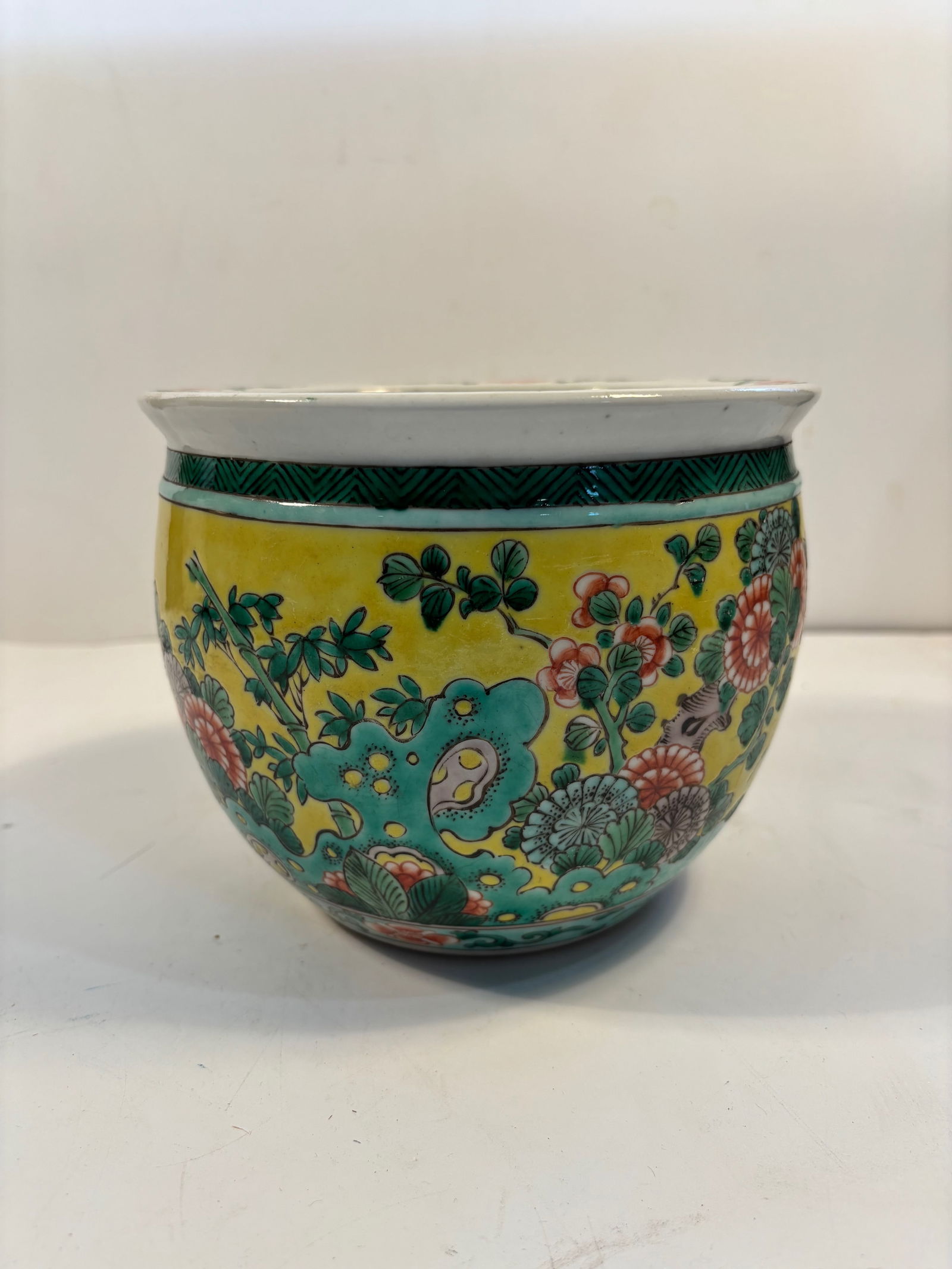 A Chinese Famille Verte porcelain jardinière: Qing Dynasty (1644-1912);Rich enamels in green, yellow, red, and turquoise depicting flowers and rocks ; Dimensions?Height: 6 INCHES ; Diameter: 6.25 INCHES.