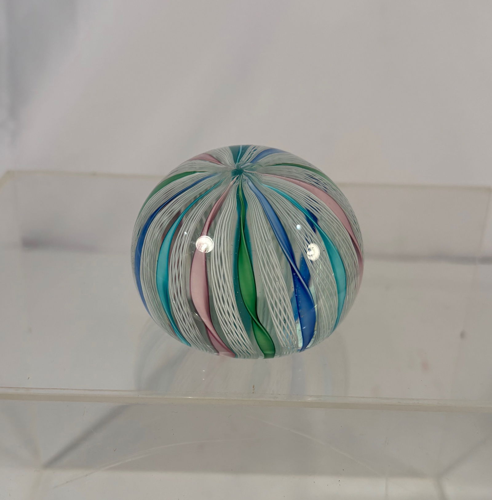 Murano Art Glass Swirl Paperweight with Multicolor Ribbon Canes: Murano art glass swirl paperweight featuring multicolor ribbon canes in shades of blue, green, pink, and white, arranged in a radiating spiral design beneath a clear glass dome. The paperweight is