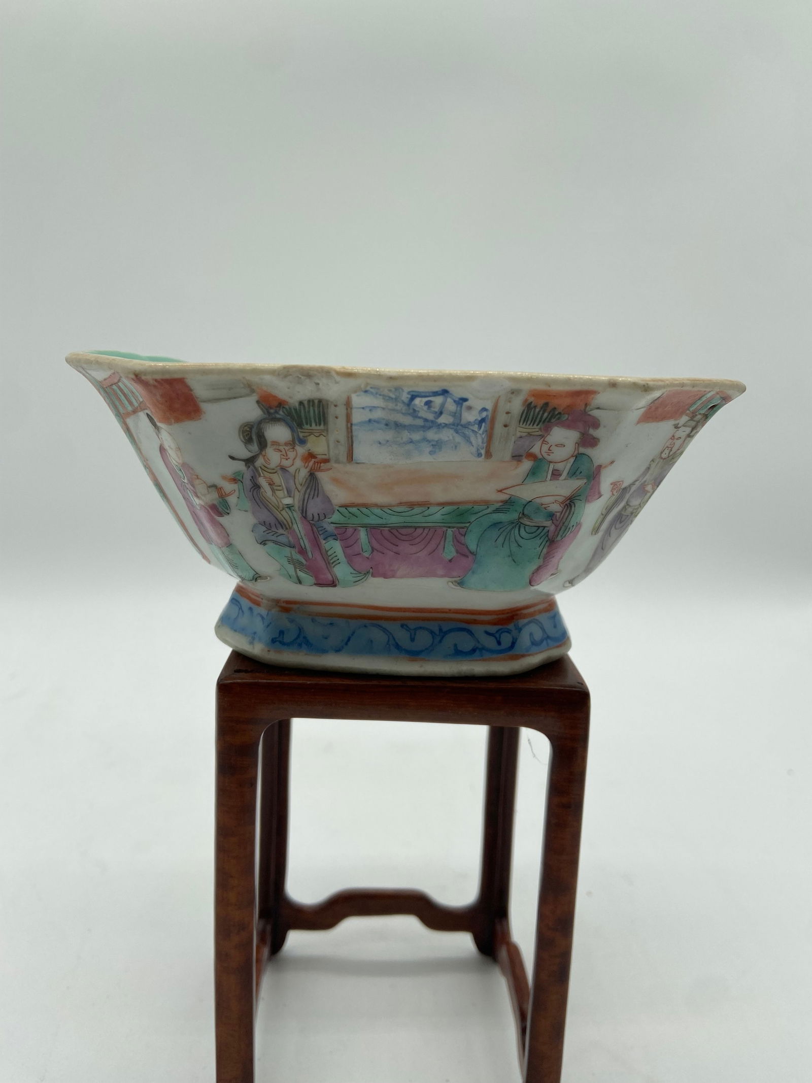 A Chinese famille rose porcelain cup with QIANLONG Four-Character mark in iron red: Qing dynasty (1644-1912); The cup depicts human figures, possibly immortals, musicians, or court attendants. Floral motifs and decorative patterns fill the surrounding space, enhancing the visual appe