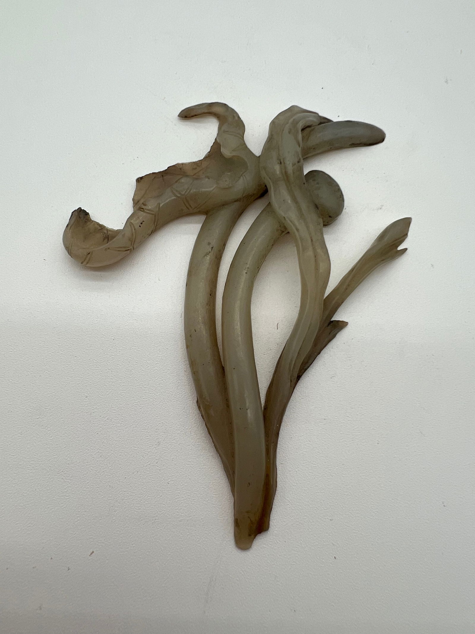 A Chinese hand carved celadon jade flower statue: Qing dynasty (1644-1912); The object in this image appears to be an abstract or naturalistic carving, possibly of a branch with vines or tendrils, which could indeed be made of celadon jade. Dimension