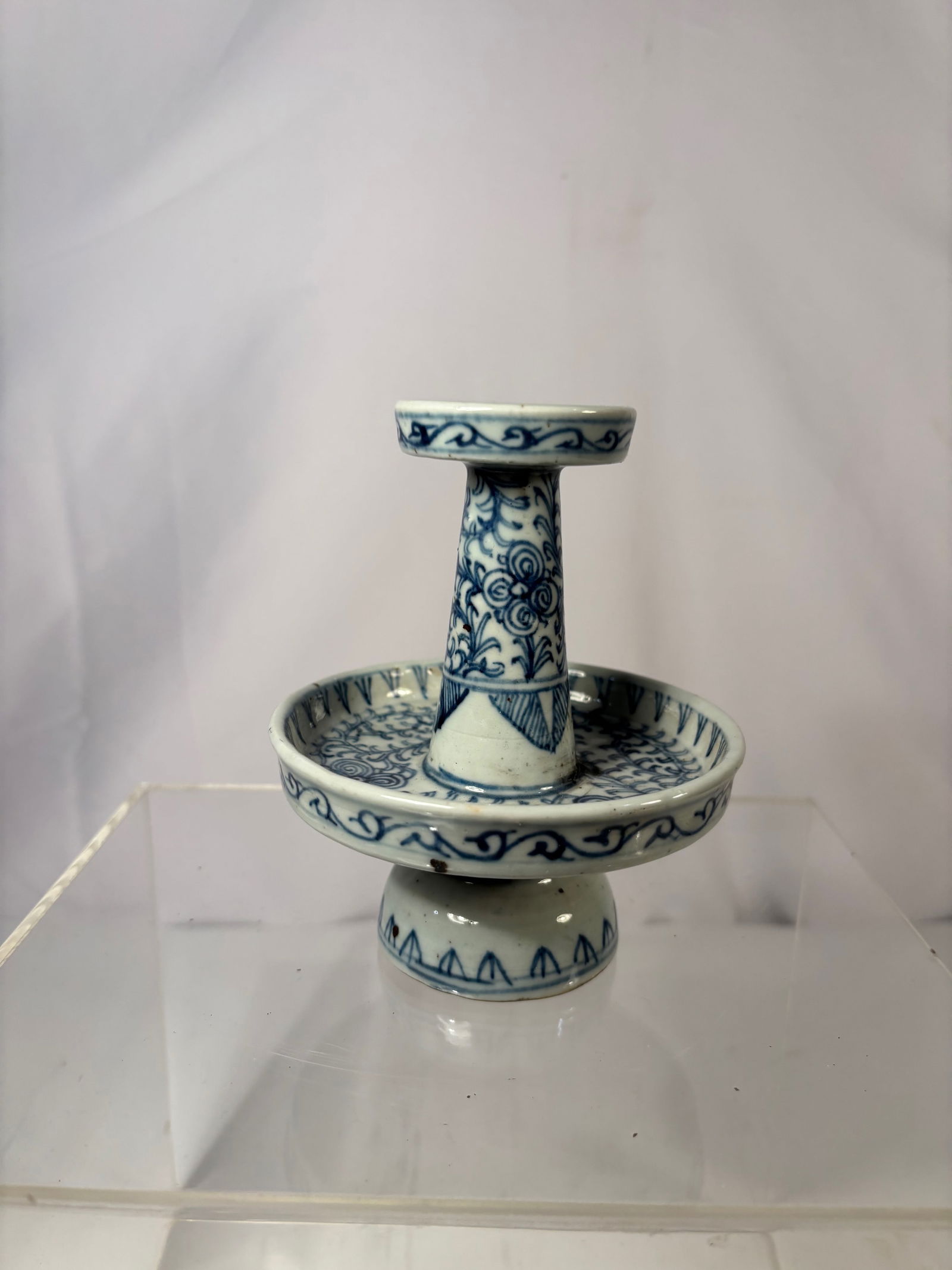 A Chinese Blue and White Porcelain Oil Lamp, Qing Dynasty: Qing dynasty(1644-1912); The oil lamp is finely potted with a wide circular drip tray supporting a tapered hollow stem rising to a small cup-shaped oil reservoir pierced with a central hole. The surfa