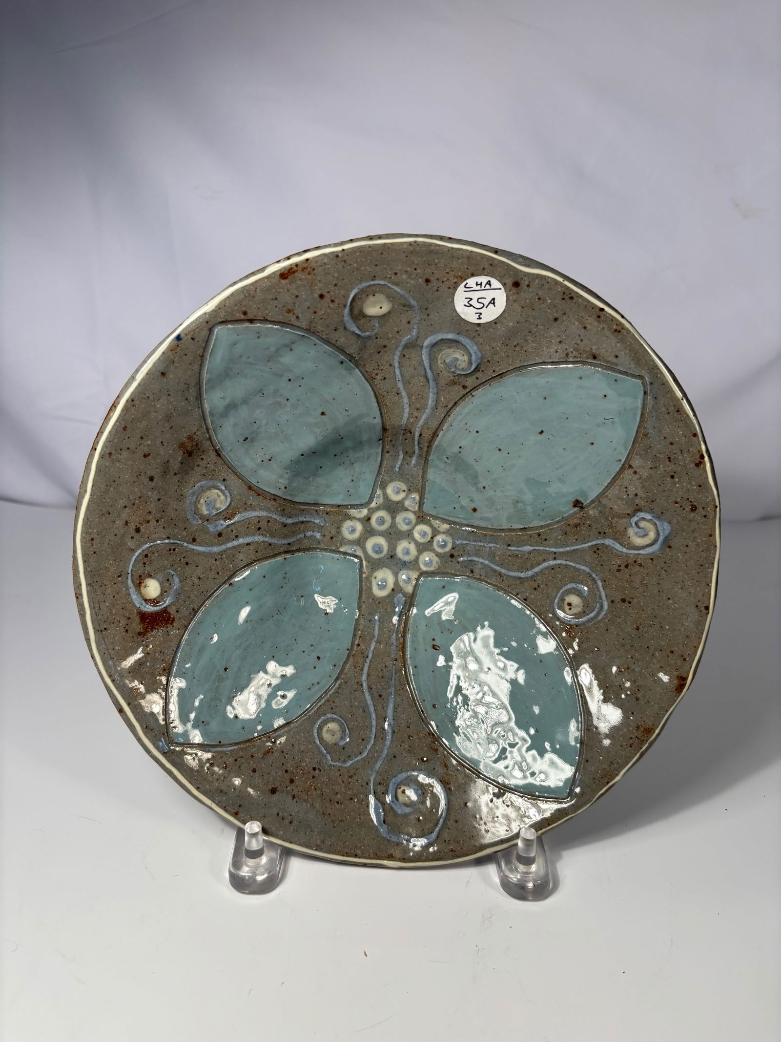 A pottery bowl with Turquoise Floral Design: Early 20th century, Of shallow circular form, the interior decorated with a stylized four-petal floral motif in turquoise and white slip, outlined with incised lines and swirling tendrils against a sp