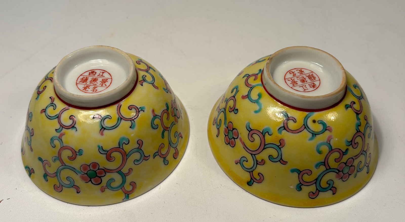 A pair of Chinese Famille Jaune-Style Porcelain Bowls with mark: Republic period (1912-1949) ; Each finely enameled on a bright yellow ground with colorful scrolling lotus and foliage motifs in the Qing dynasty style. The interior is left undecorated in white glaze