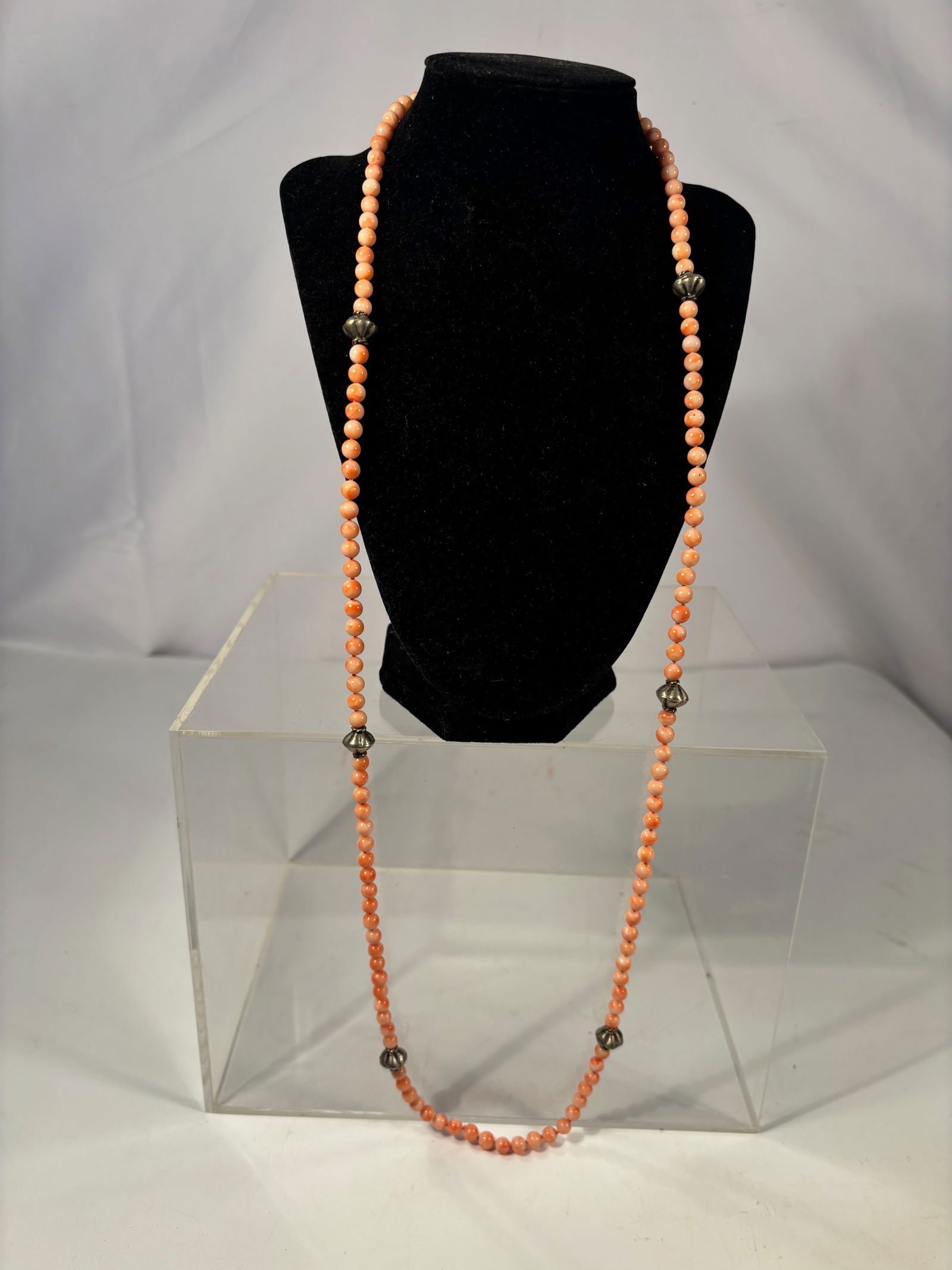 Vintage Coral Bead Necklace with Silver-Tone Spacers, 37 Inches: A vintage necklace composed of small round coral beads, measuring approximately 37 inches in length. The strand is accented with silver-tone metal spacer beads (material untested). The coral beads dis