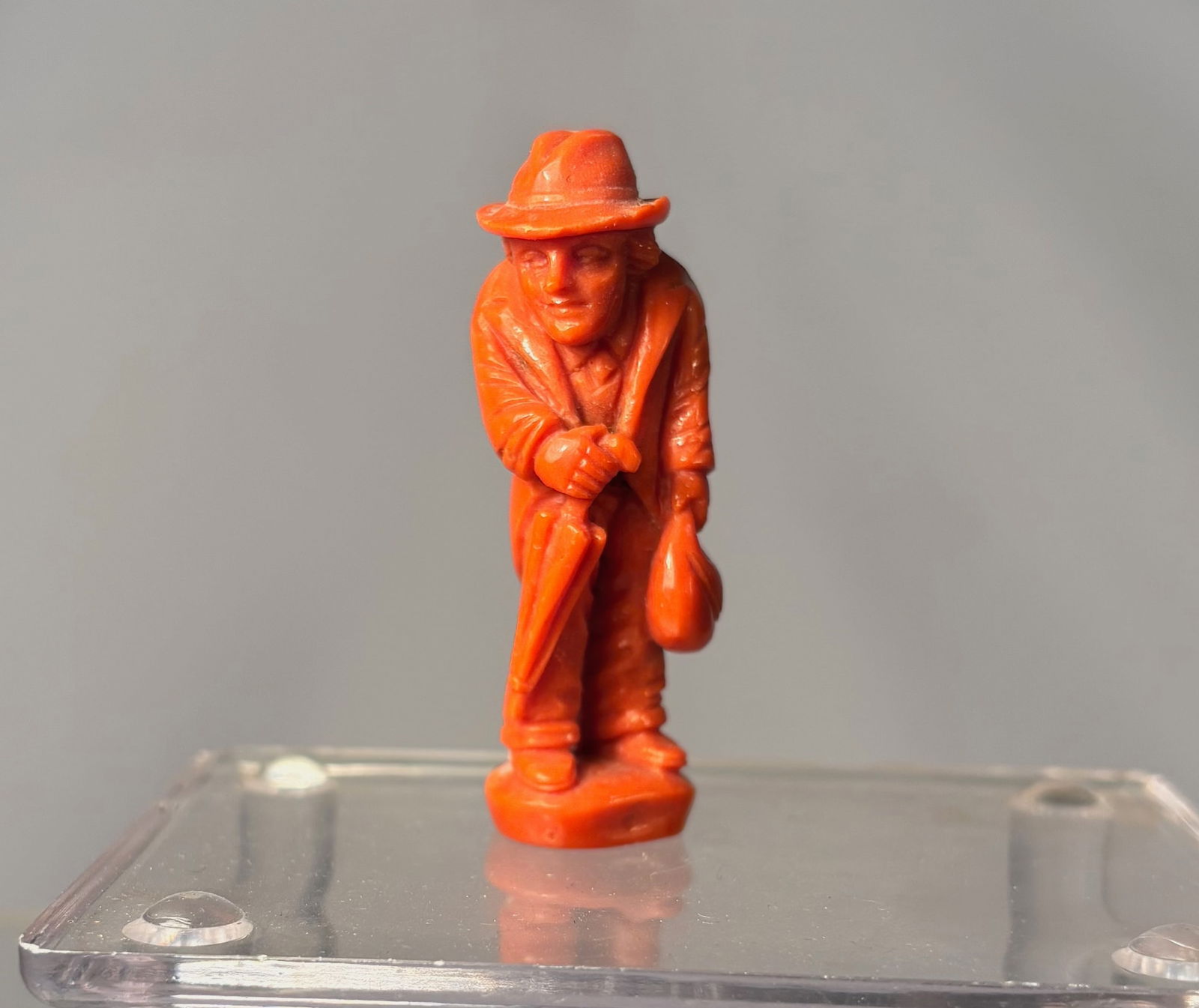 A Mediterranean Coral Carved Figure of a Gentleman: An antique carved figure executed in natural Mediterranean coral, depicting a standing gentleman wearing a hat and holding an umbrella. The figure is finely carved in the round, with well-defined faci
