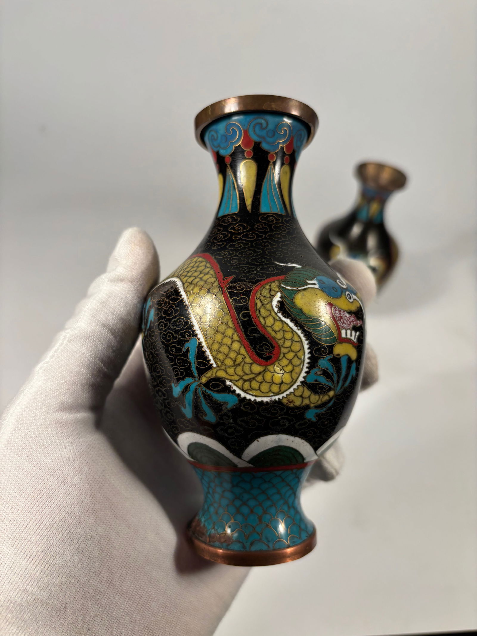 Pair of Chinese Cloisonné Enamel Vases with Five-Clawed Dragons: Qing Dynasty(1644-1912); A decorative pair of Chinese cloisonné vases, each finely enameled with vibrant imagery of a five-clawed imperial dragon in pursuit of a flaming pearl, set against a black gr