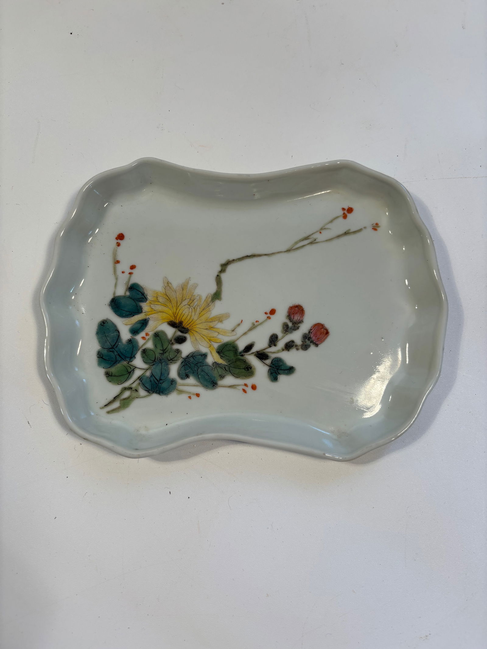 A Chinese famille rose porcelain ink-washer plate: Late 19th to early 20th, It’s a refined depiction of chrysanthemums, buds, and leaves .Dimensions? Length: 7 inches; Width: 5.25 inches; Height: 0.5 inches.