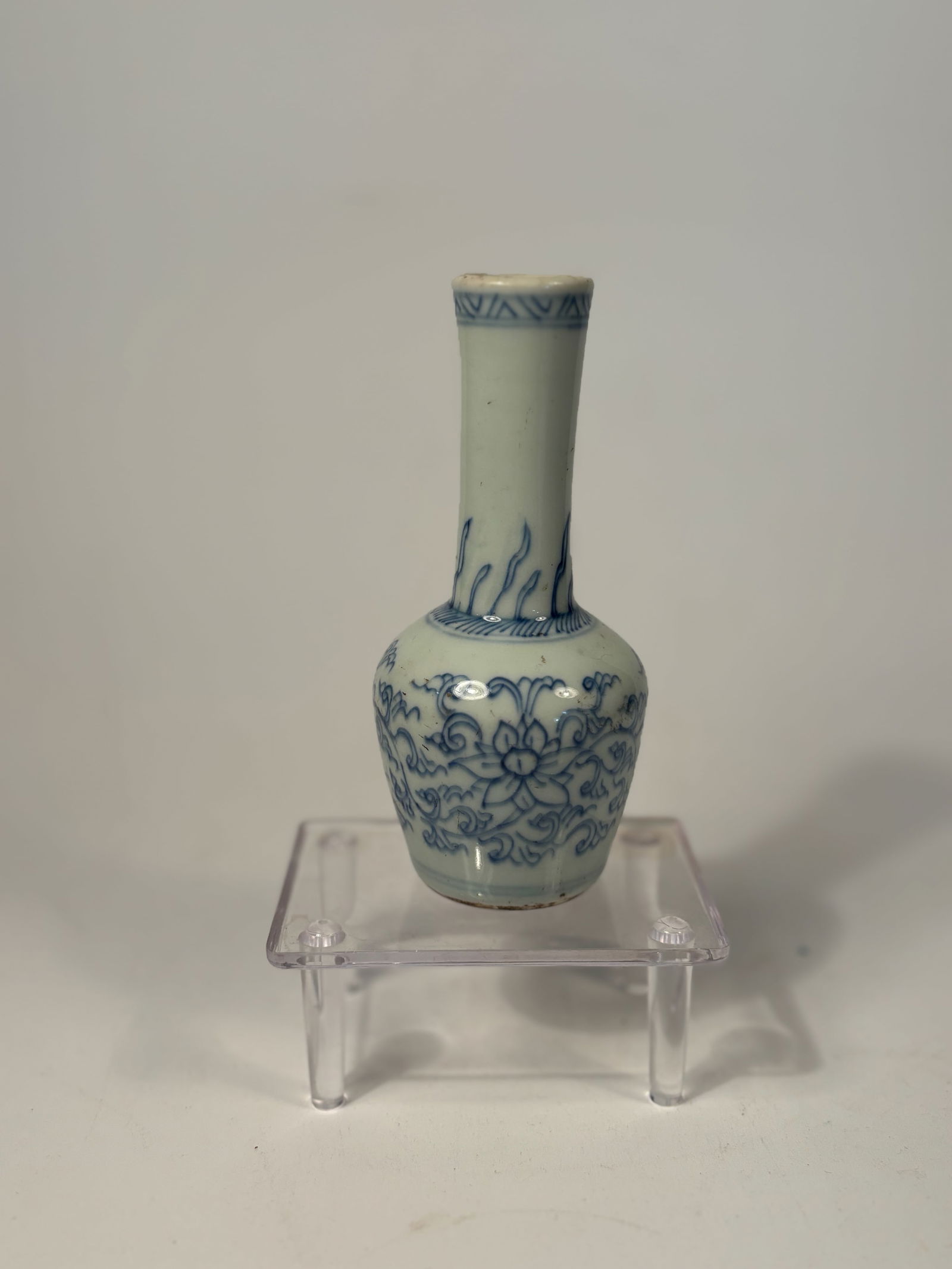 A Chinese blue and white porcelain vase, Yongzheng or early Qianlong period: 18th century, The vase features a slender neck and globular body rising from a short, unglazed foot. The body is delicately decorated in underglaze cobalt blue with continuous lotus scroll motifs, sty