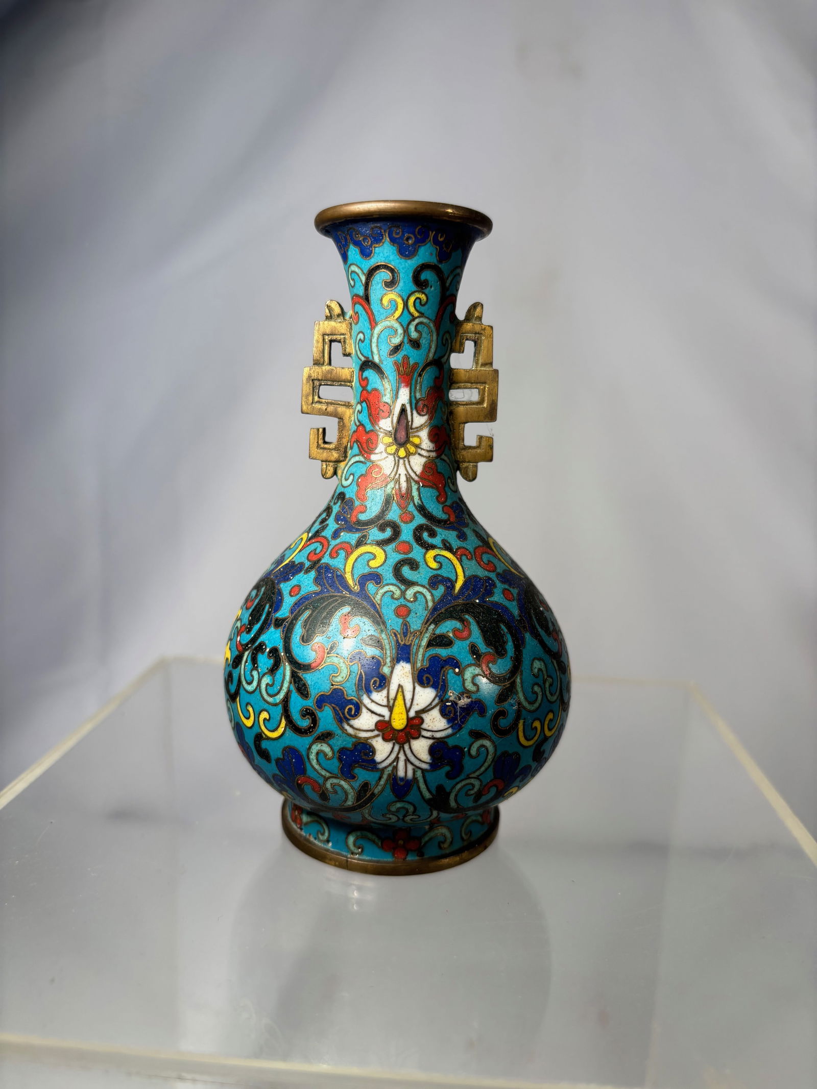 A Chinese Cloisonné Vase with Ruyi Handles, 18th- 19th centruy: Chinese cloisonné vase of baluster form, decorated with scrolling lotus and foliate motifs on a turquoise ground, executed in shades of blue, yellow, red, and white enamels. The neck fitted with a