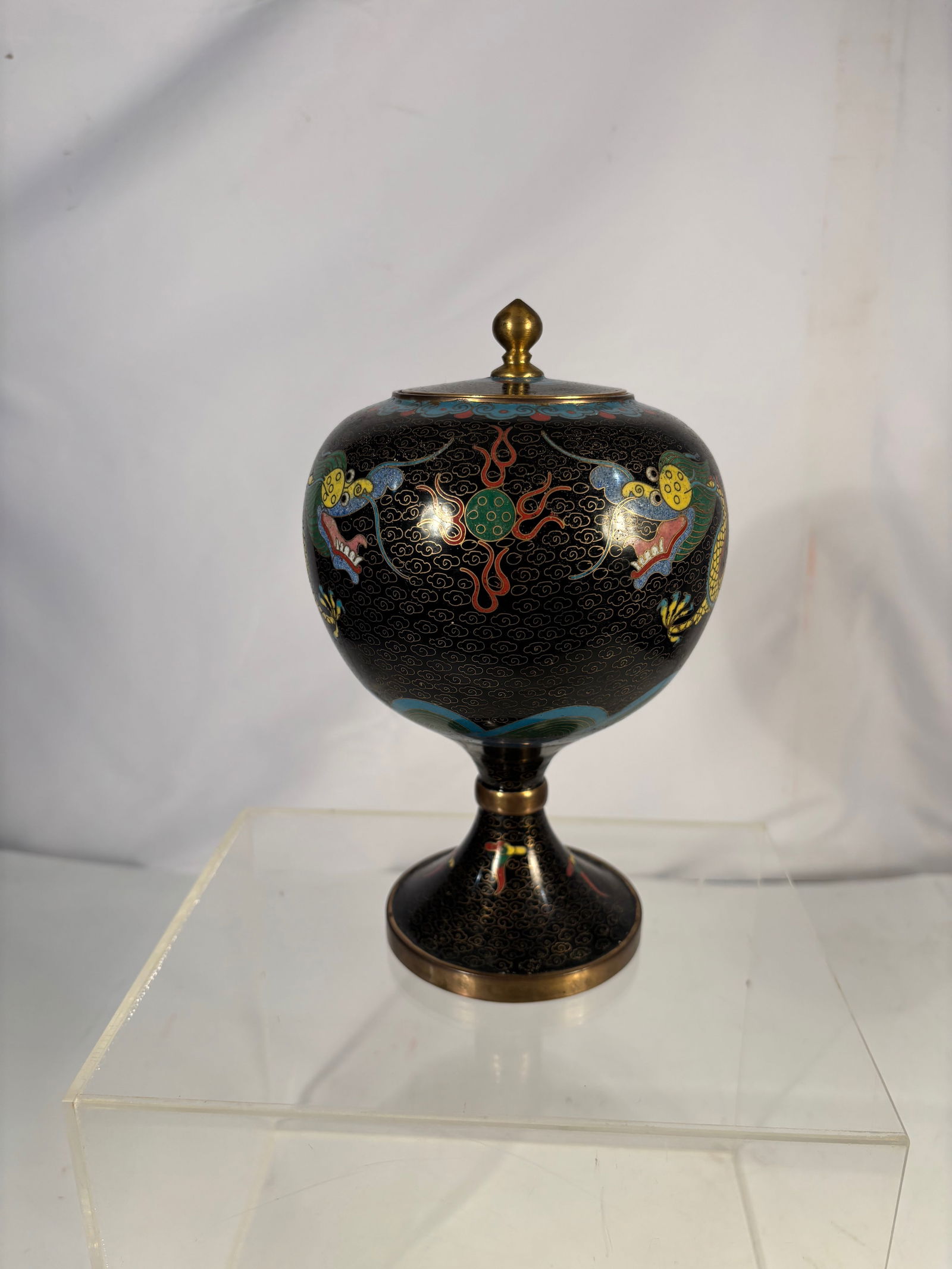 A Chinese Cloisonné Enamel Covered Censer with Dragon Motif: A Chinese cloisonné enamel covered censer of rounded form, decorated with vibrant dragon motifs amidst scrolling cloud patterns on a black ground. Executed in polychrome enamel with fine wirework det