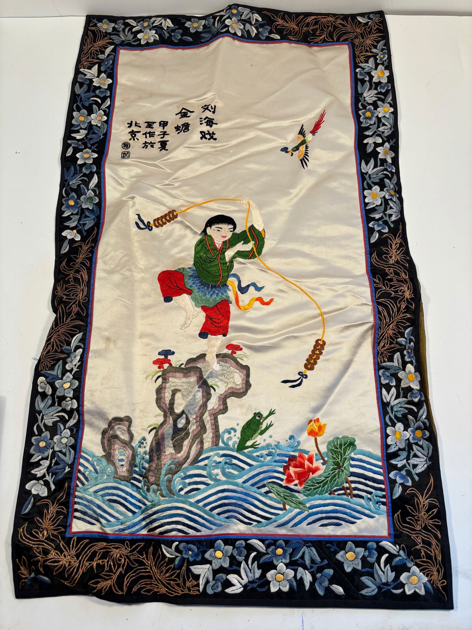 A Chinese silk embroidered panel: The figure (possibly a child or acrobat) is shown in motion with bright, exaggerated clothing ; Dimensions?Length: 29.5 inches; Width: 17 inches.