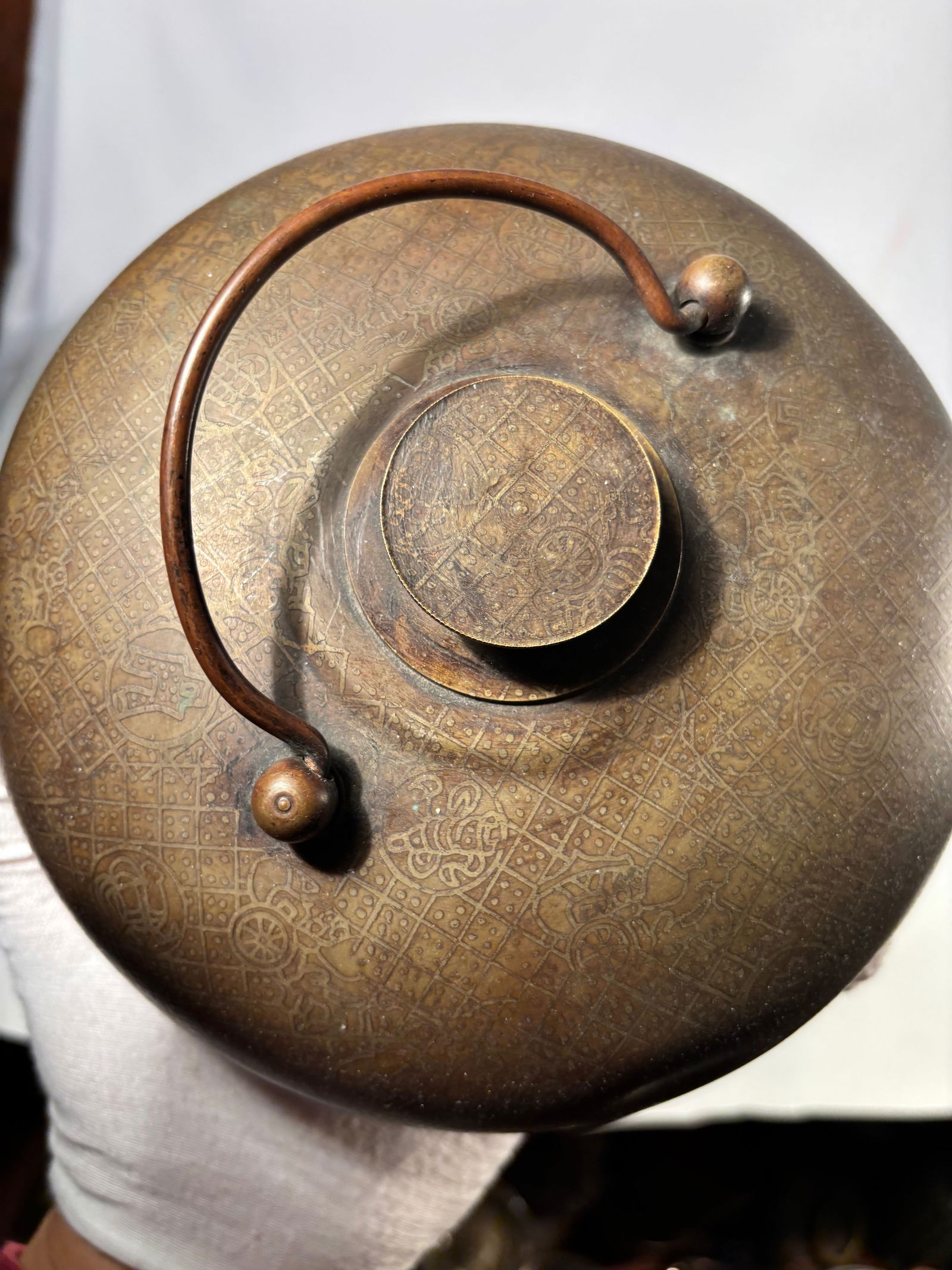 A Chinese Bronze Hand Warmer with Engraved Decoration, Daoguang Mark: Chinese bronze hand warmer with domed cover and arched handle. The surface finely engraved with geometric and auspicious decorative motifs. The base bearing a Daoguang mark. Diameter: 7.5 inches; Heig