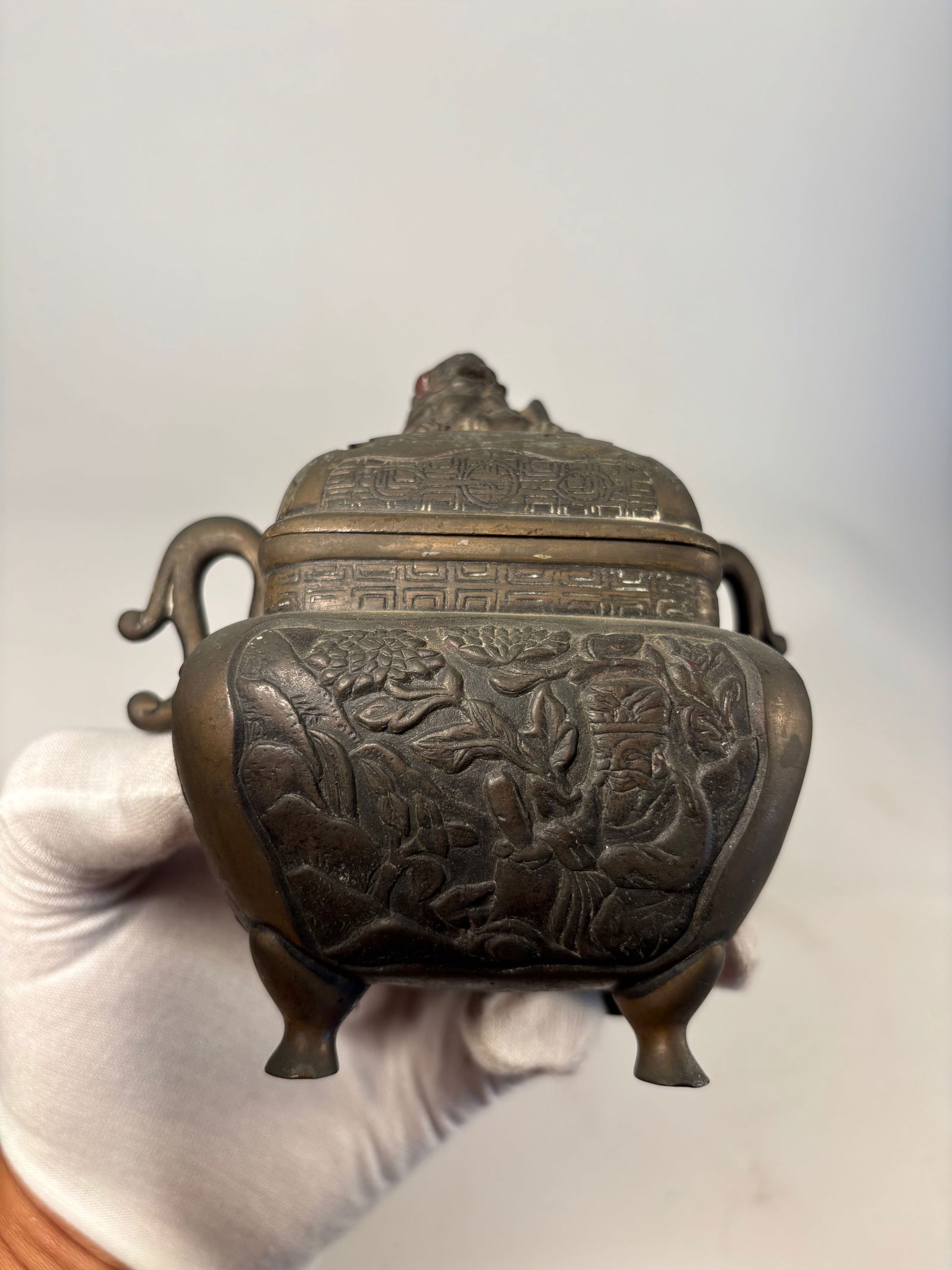 A Chinese bronze censer with cover: Qing Dynasty(1644-1912), A finely cast antique Chinese bronze censer with detailed figural relief and a pierced lid surmounted by a foo dog finial. The body features two relief scenes: one side depict