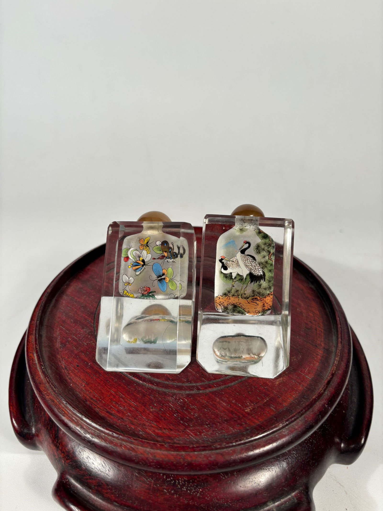 A Pair of Inside-Painted Rock Crystal Snuff Bottles: Likely Republic period, early 20th century. Each of square section and finely painted on the interior, one bottle depicting a pair of cranes standing beneath pine trees, symbolizing longevity and