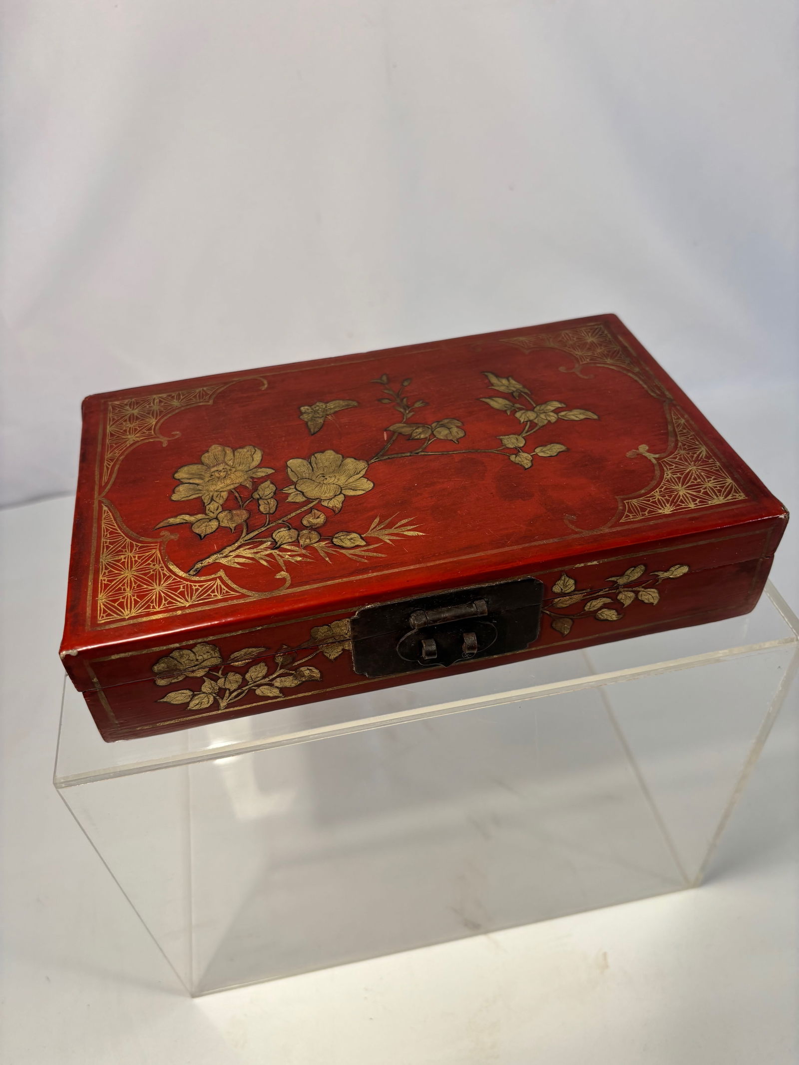 A Japanese Red Lacquer Box with Gilt Floral Motif, Meiji (1868–1912): A fine Japanese red lacquer (urushi) box, rectangular in form with gilt maki-e decoration of blooming flowers and scrolling foliage on the cover and sides. The corners feature delicate geometric motif