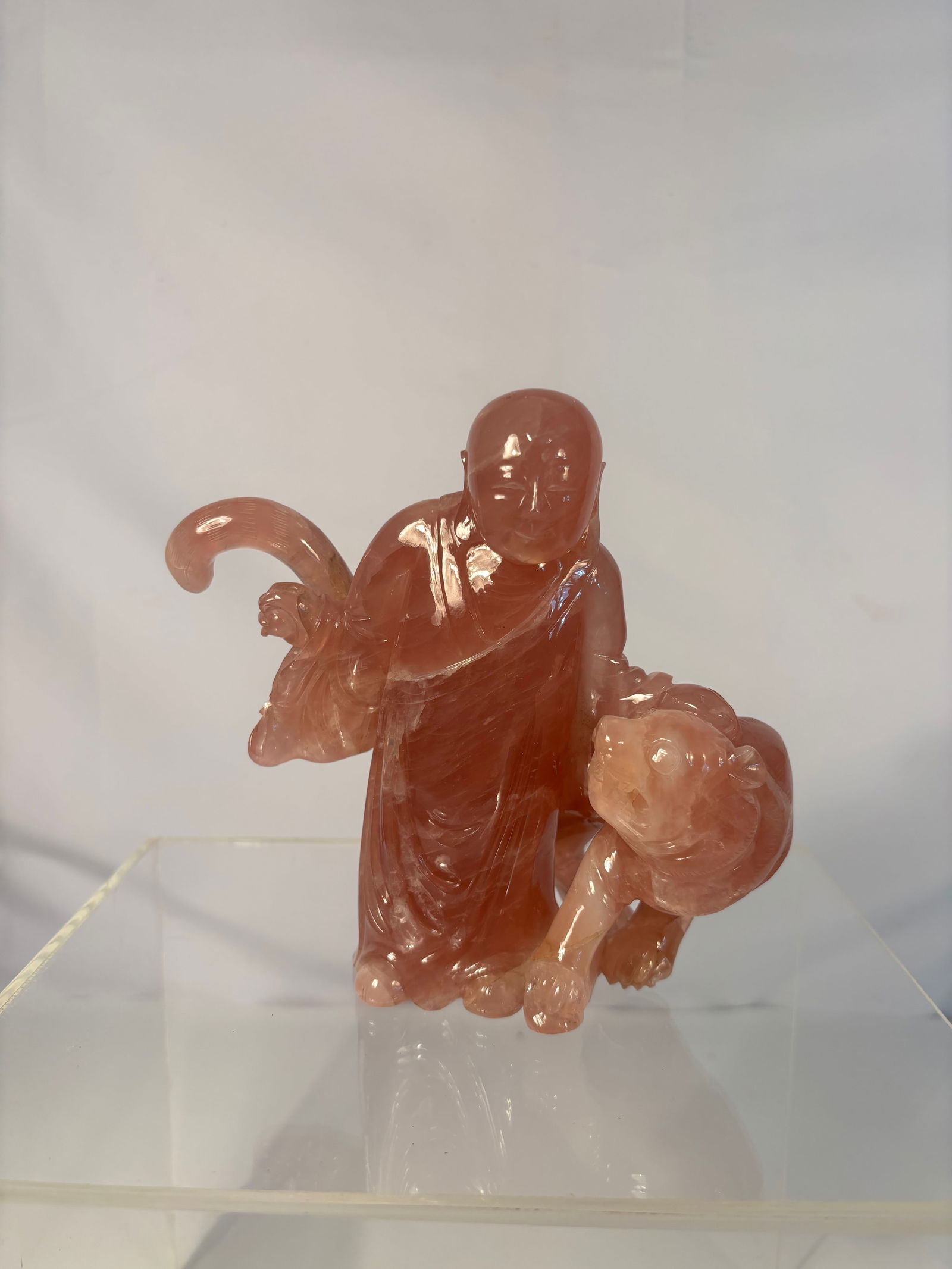 A Chinese Fluorite (‘Furong Stone’) Figure of a Luohan with tiger: Qing Dynasty(1644-1912); The staue depicted a LUOHAN standing with flowing robes, holding a staff, and accompanied by a tigerat his side. The stone with natural striations and inclusions utilized to