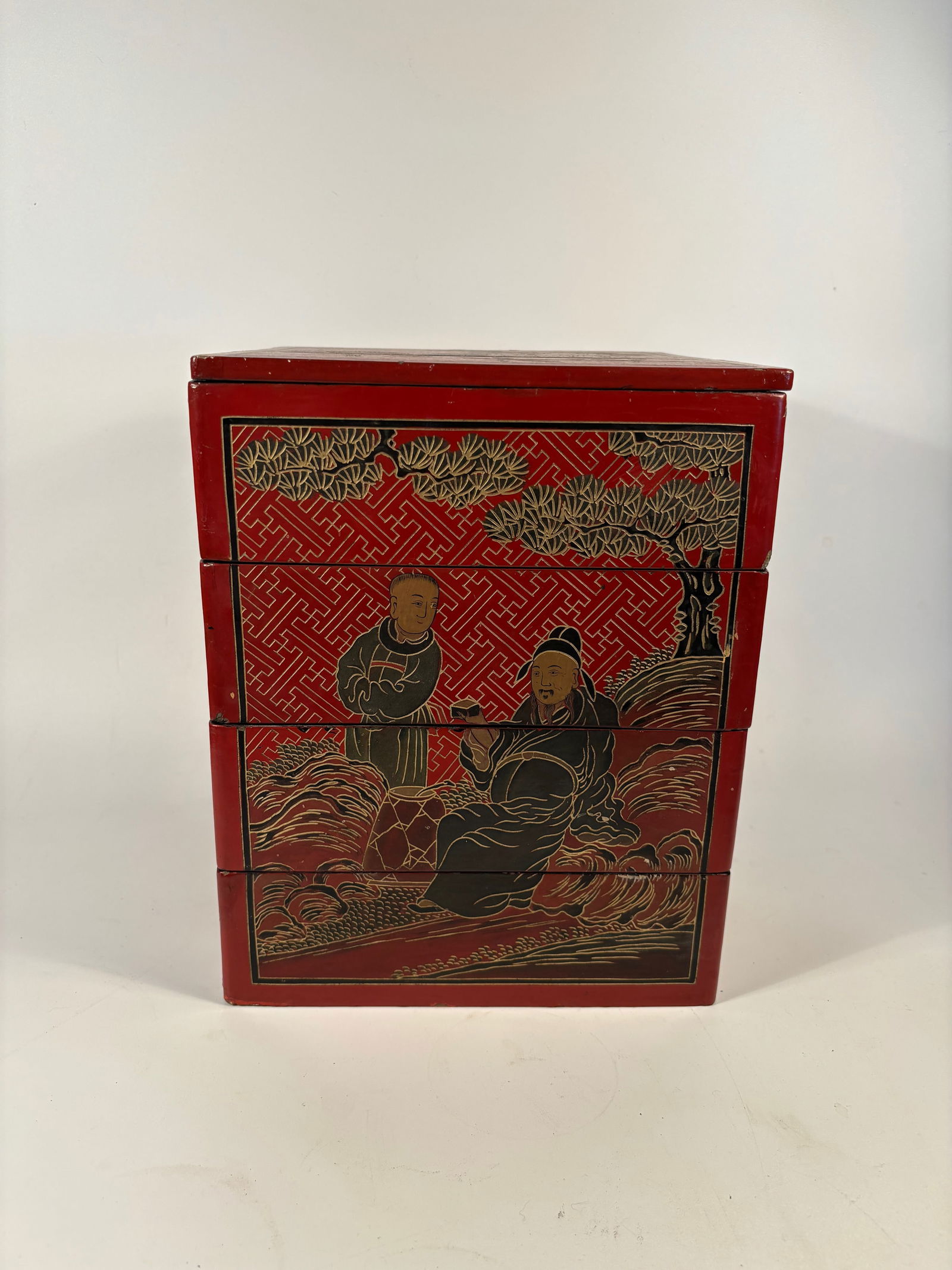 A Chinese red lacquer hand painted box: Qing dynasty(1644-1912);a multi-tiered lacquer storage or food box ;The figures, landscape, and florals suggest classical Chinese scholarly or Daoist themes.Dimensions?Height: 11 inches. Width: 8.5 in