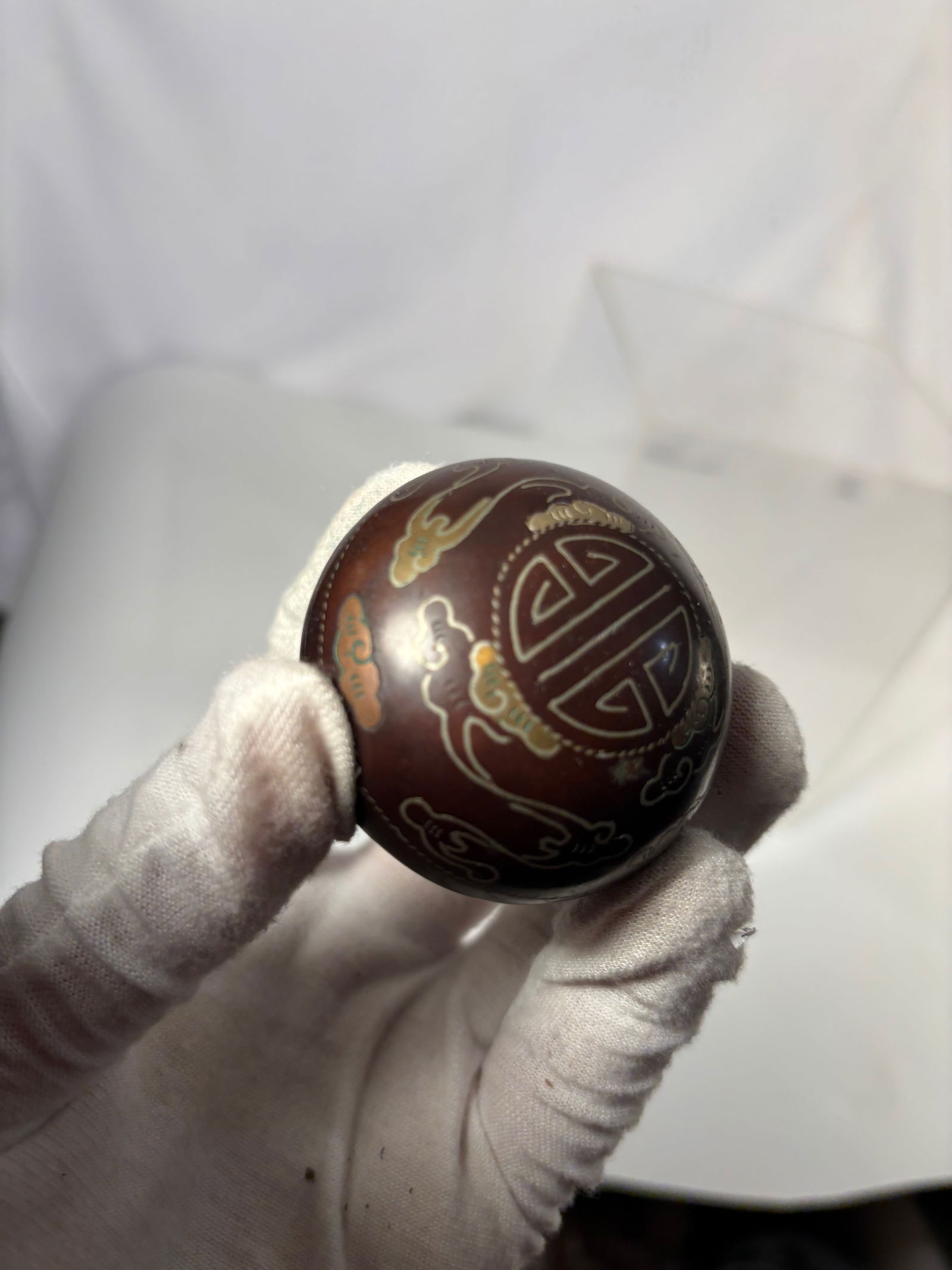 A Chinese Silver Inlaid Metal Longevity Motif Covered Box: Chinese small metal box of rounded form, decorated with silver inlaid longevity character and cloud motifs. The domed cover and body are finely ornamented with stylized patterns in contrasting metal.