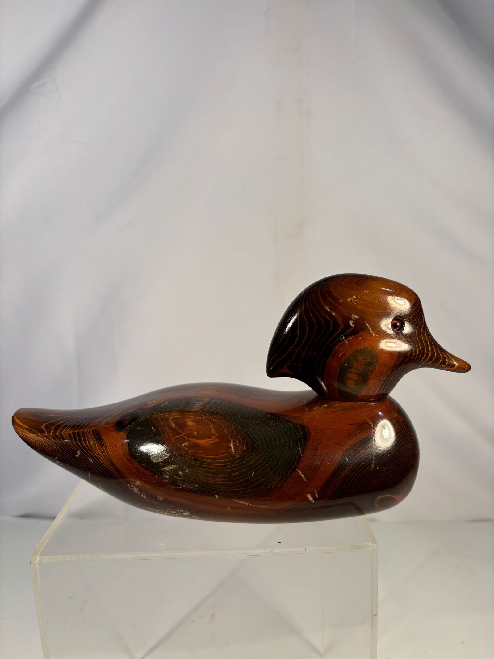 John E. Bundt Hand-Carved Wooden Duck Decoy, Signed and Branded: A hand-carved wooden duck decoy signed John E. Bundt, featuring a well-balanced, streamlined form and a rich natural wood surface with visible grain. The underside bears a branded workshop mark with