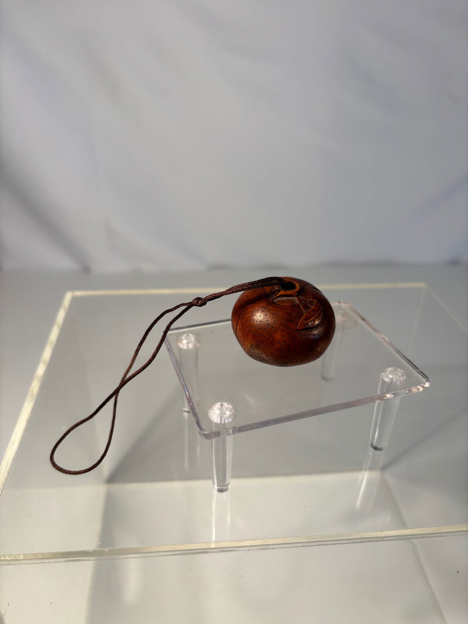 A Japanese Carved boxwood Netsuke of a Chestnut with Interior Figure: Meiji period(1868-1912) ,A Japanese carved wood netsuke, fashioned as a chestnut with naturalistic veining, the form opening to reveal a finely carved interior figure. Smooth, warm patina with himotos