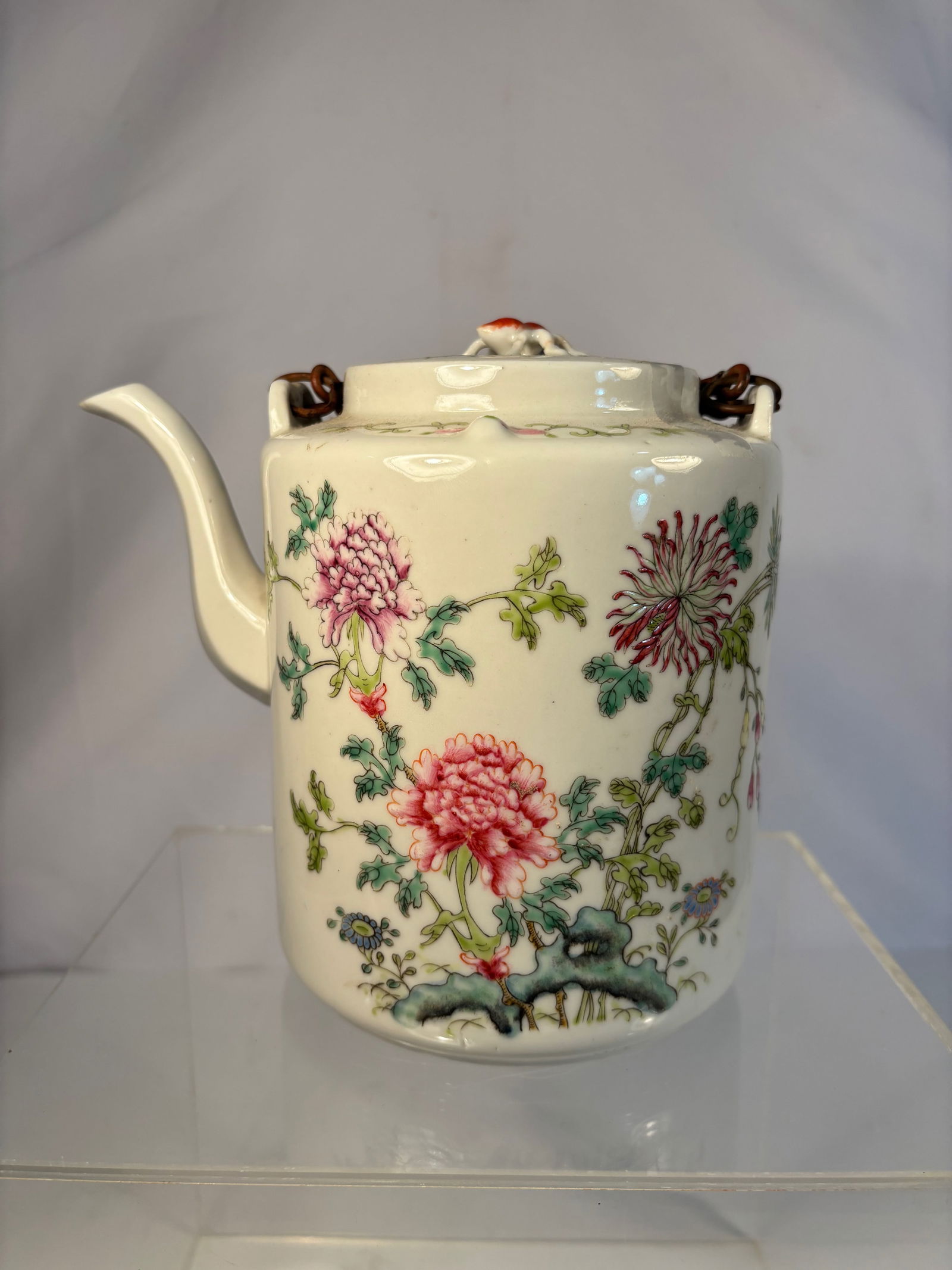 A Famille Rose Porcelain Teapot with Chrysanthemums, Marked "Hongxian Nian Zhi": (1915-1916);Finely painted Republic period porcelain teapot decorated in famille rose enamels with blossoming chrysanthemums growing from rockwork, symbolizing longevity and nobility. The cylindrical