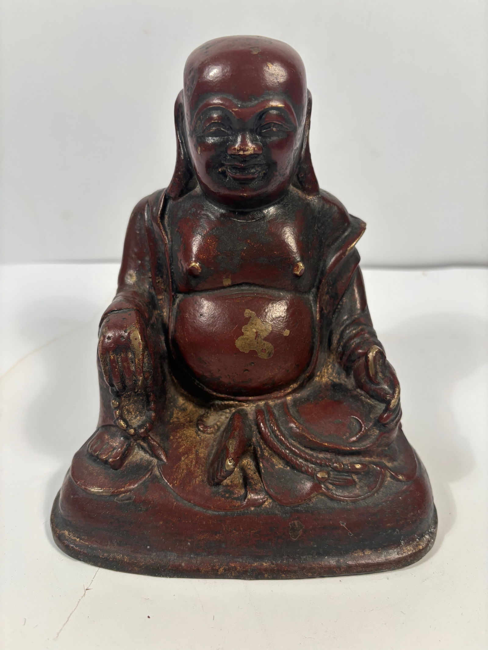 A Chinese gilted and red lacquered bronze Happy buddha Statue: Qing Dynasty (1644-1912), Traces of gold leaf or paint are still visible, particularly on the belly and garments; Dimensions?Height: 7 inches .