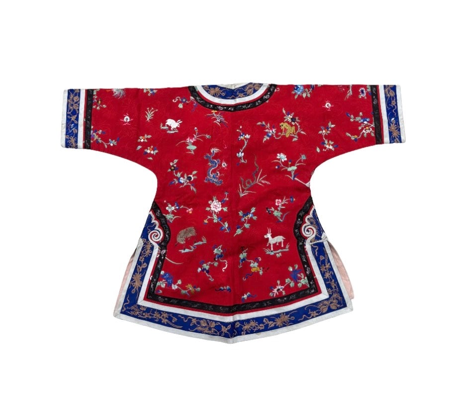 A Chinese silk embroidered woman’s jacket: Qing dynasty(1644-1912); A striking red silk woman’s jacket featuring finely executed embroidery in silk floss and metallic threads. The robe is elaborately decorated with auspicious motifs includin