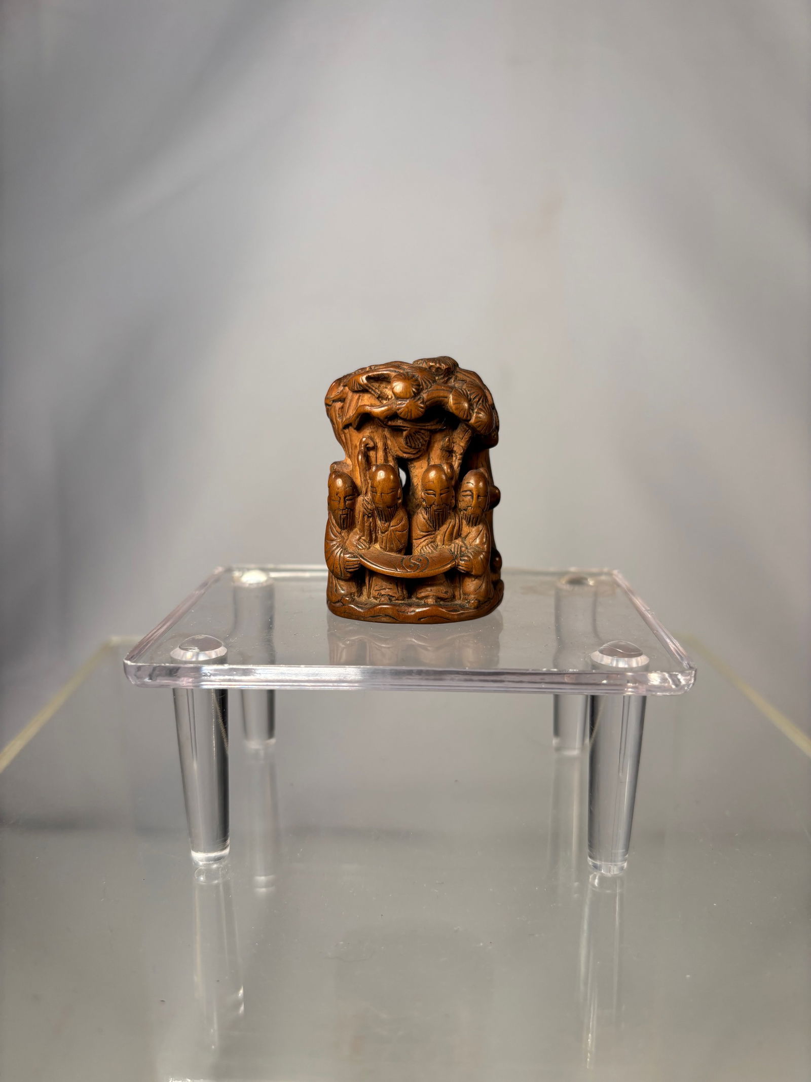 A Chinese Carved Boxwood Seal with Immortal Figures and Shou Medallion Base: Qing Dynasty (1644-1912); A Chinese carved boxwood seal finely worked with a detailed figural scene depicting immortals and attendants arranged in a layered composition. The figures are carved in high