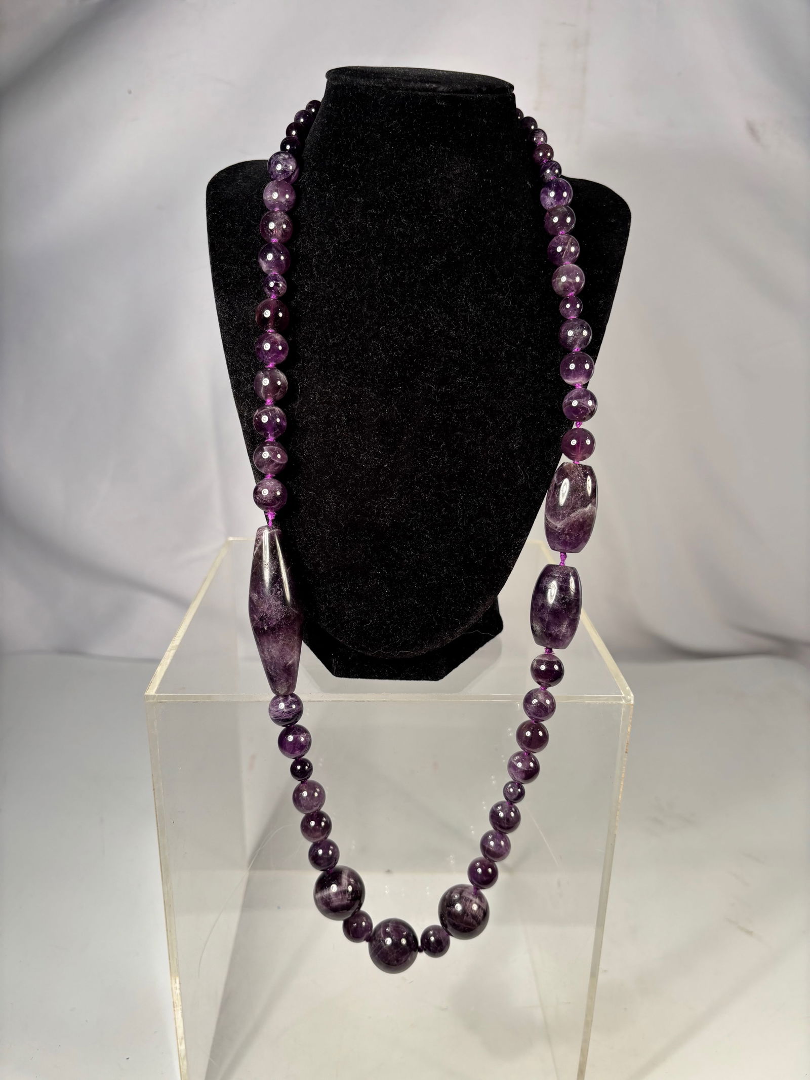 A Natural Amethyst Bead Necklace 180grams: Vintage necklace composed of graduated polished amethyst beads including several large elongated beads measuring up to approximately 60 mm. The stones display natural purple coloration with internal i
