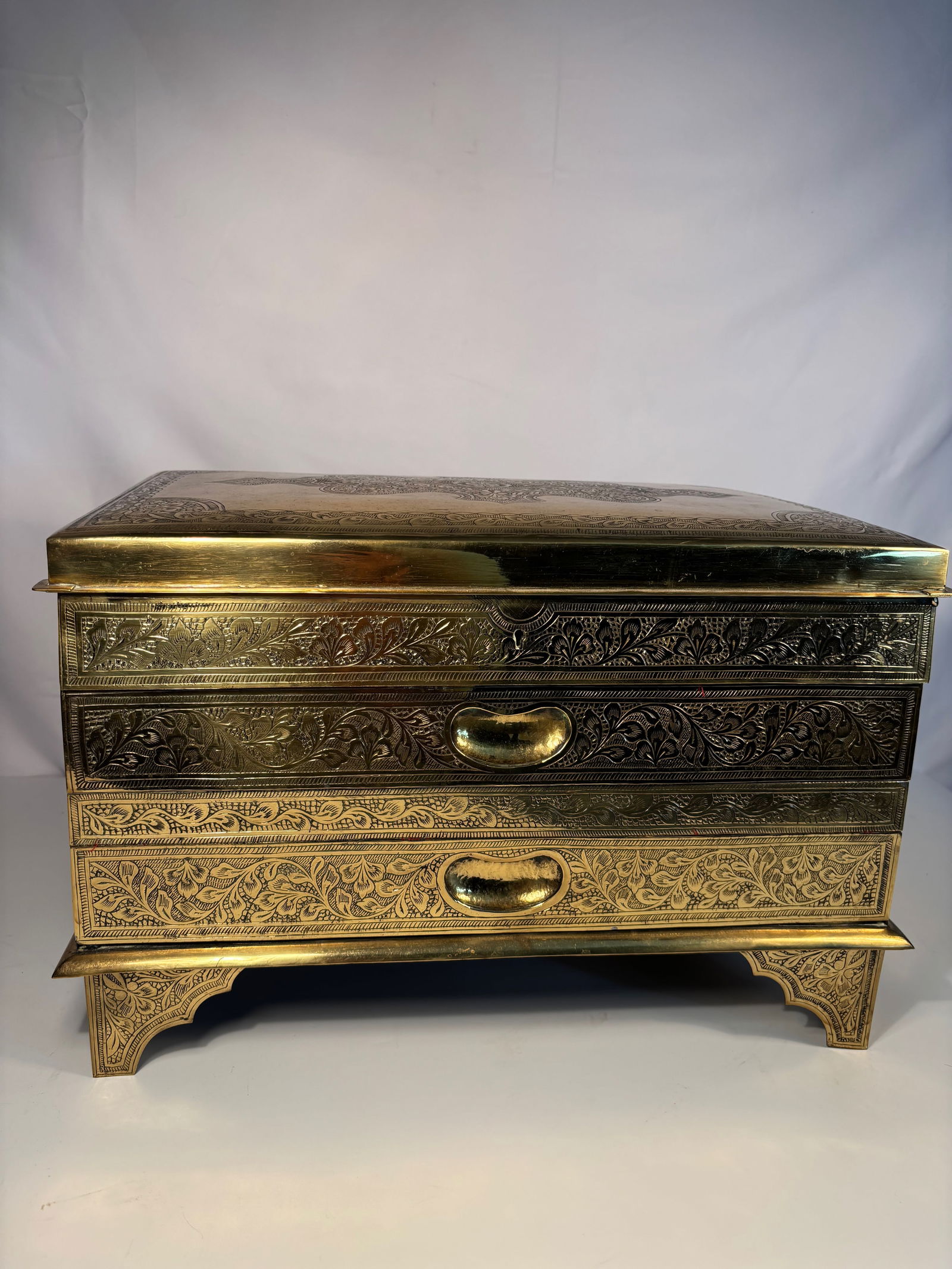 A Hand-Engraved Brass Chest, Velvet Lined, Indian/Middle Eastern,: 19th -20th century; A rectangular chest with hinged cover and two fitted drawers, the exterior clad in polished brass richly engraved with scrolling foliate and arabesque motifs. Each side decorated w