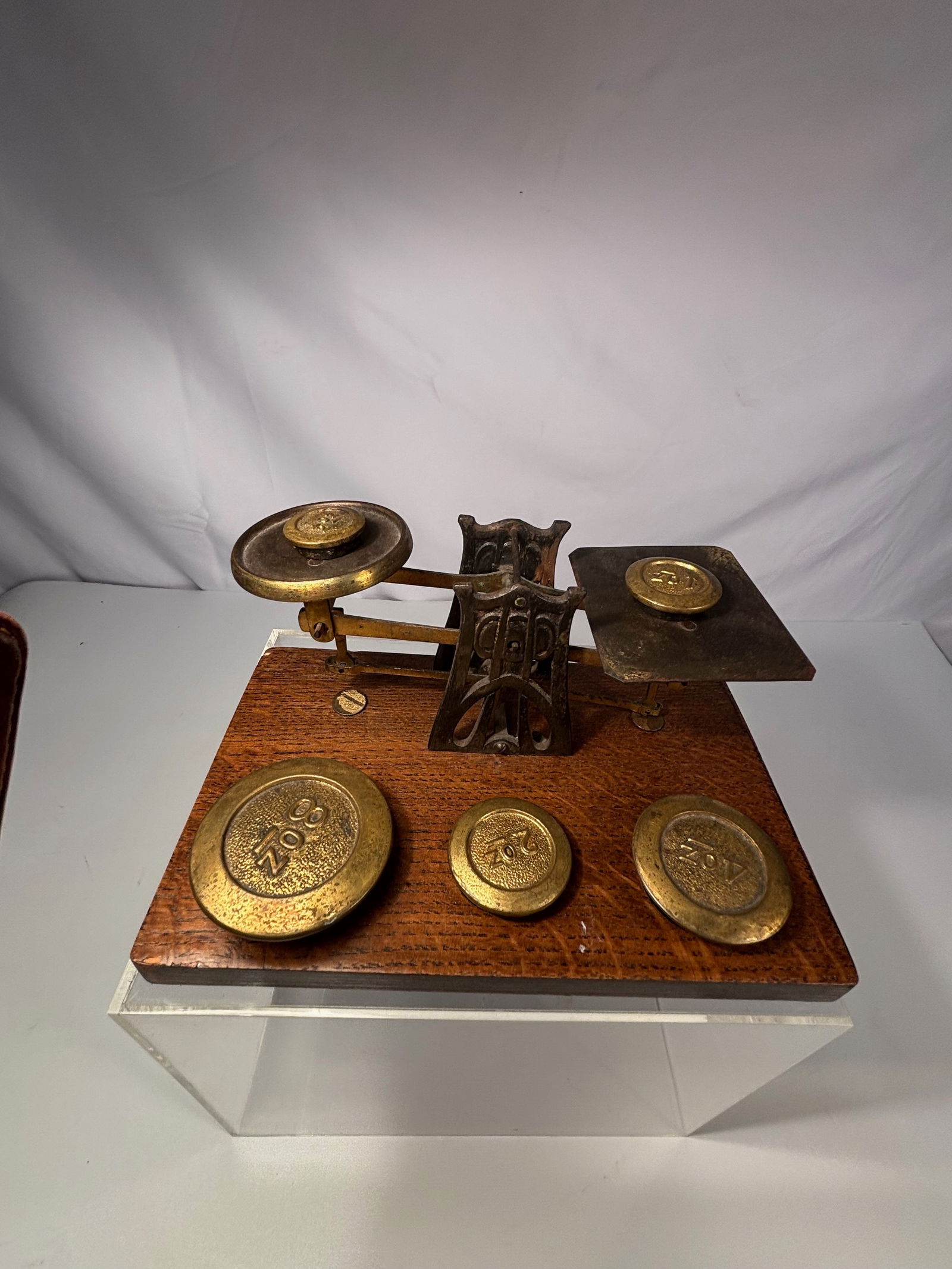 Antique Brass Balance Scale with Nested Weights on Wooden Base: An antique brass beam balance scale with a fitted wooden base and a complete graduated set of brass nesting weights. The balance features dual brass pans supported by an ornate cast iron fulcrum, moun