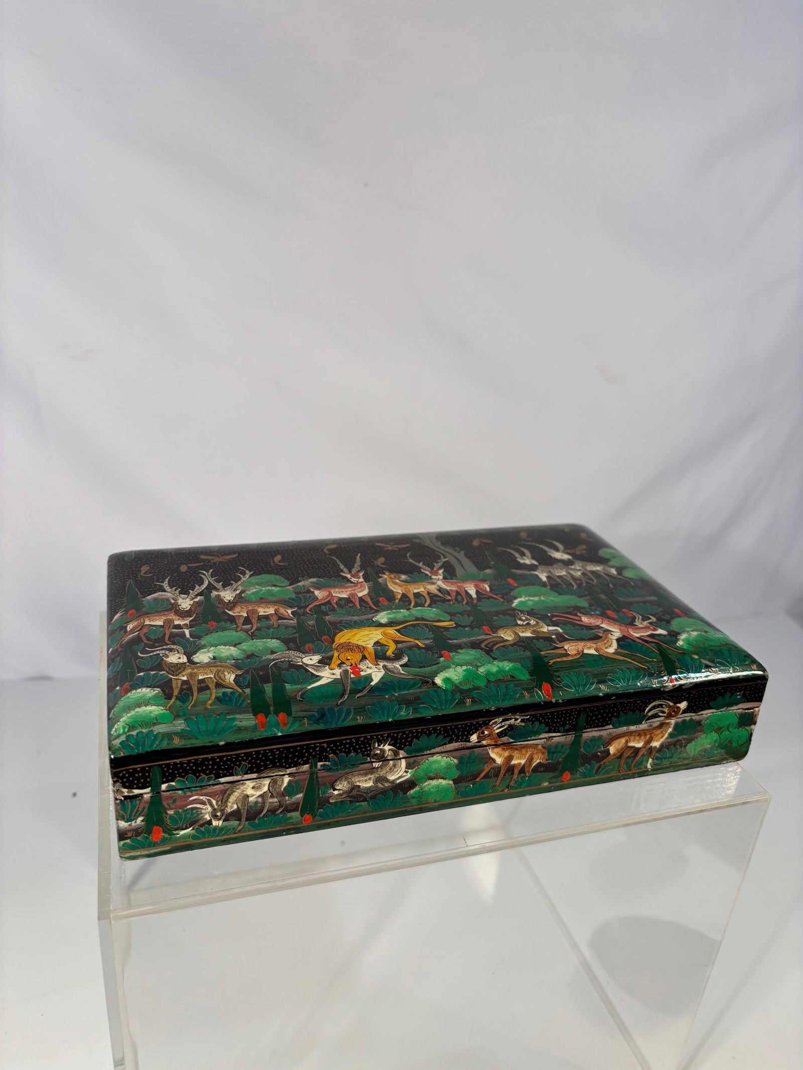 A Large Russian Palekh Lacquer Box, Hunting Scene: Early 20th century; A fine and large papier-mâché lacquer box, hand-painted with a lively hunting scene of deer, hounds, and a lion amid a forest landscape, enriched with gilt highlights and dot dec