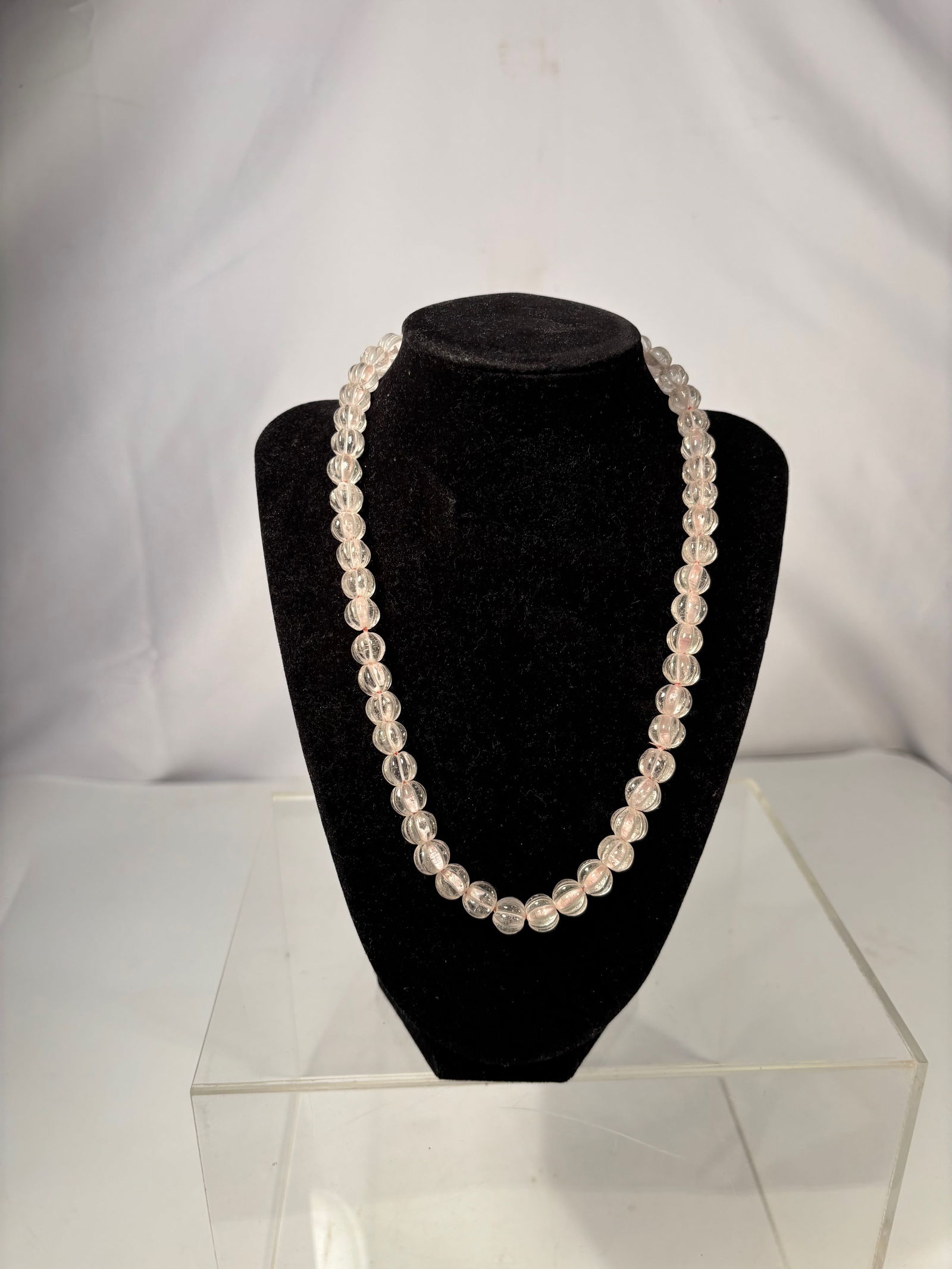 A Clear Rock Crystal Bead Necklace with Gold-Tone Clasp: This necklace is composed of clear carved beads, each formed in a melon-style shape with longitudinal grooves. The beads are transparent to lightly translucent, showing natural internal inclusions